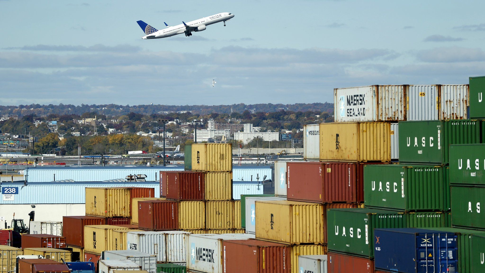 Plane flying over stack of containers