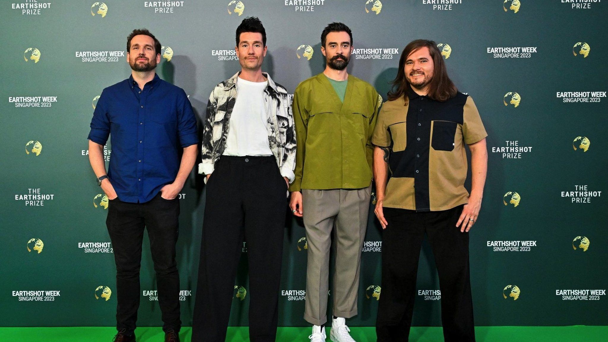 Участники инди-поп-группы Bastille позируют на зеленой ковровой дорожке