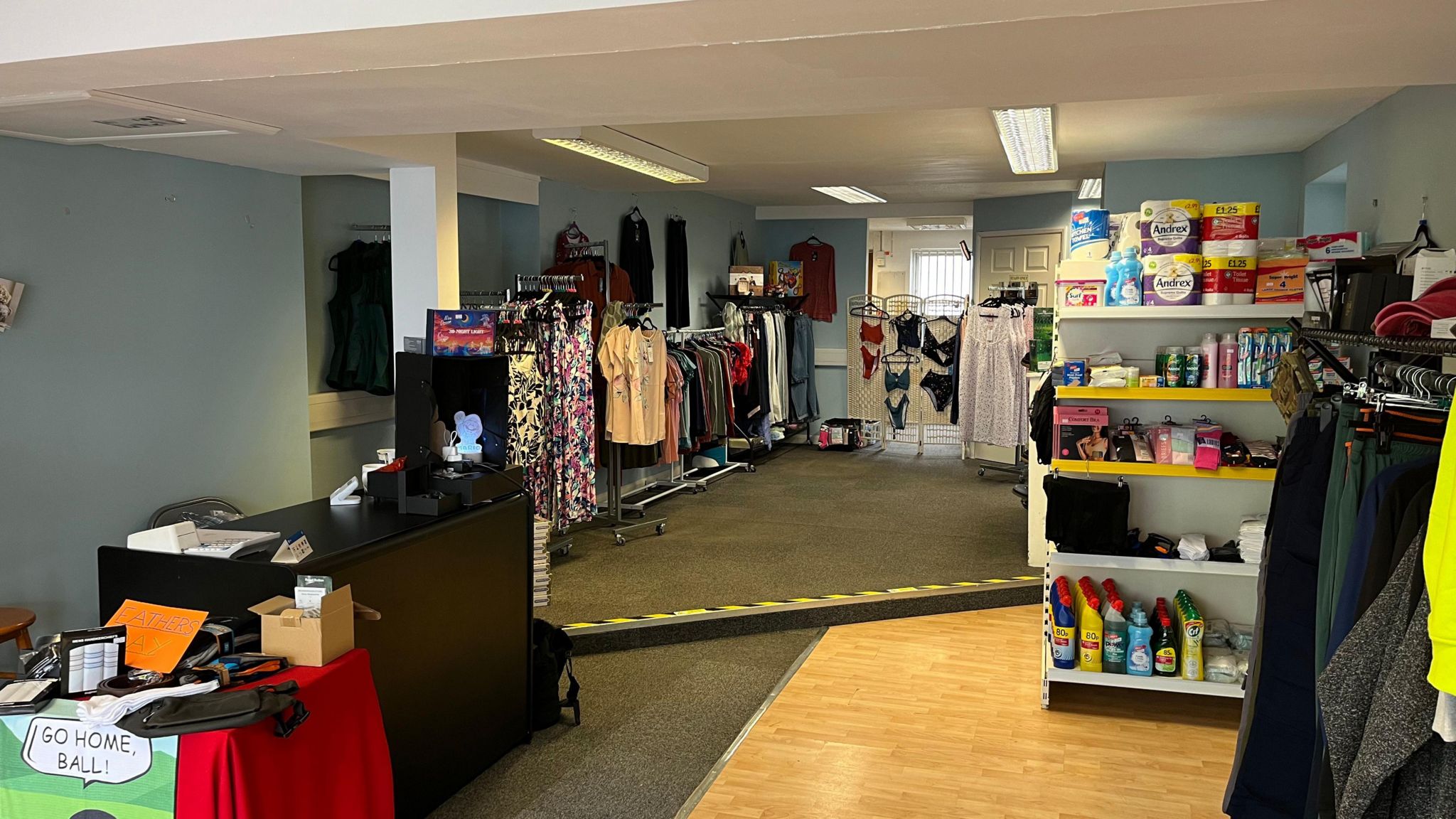 A wide shot of the shop showing clothing and toiletries. 