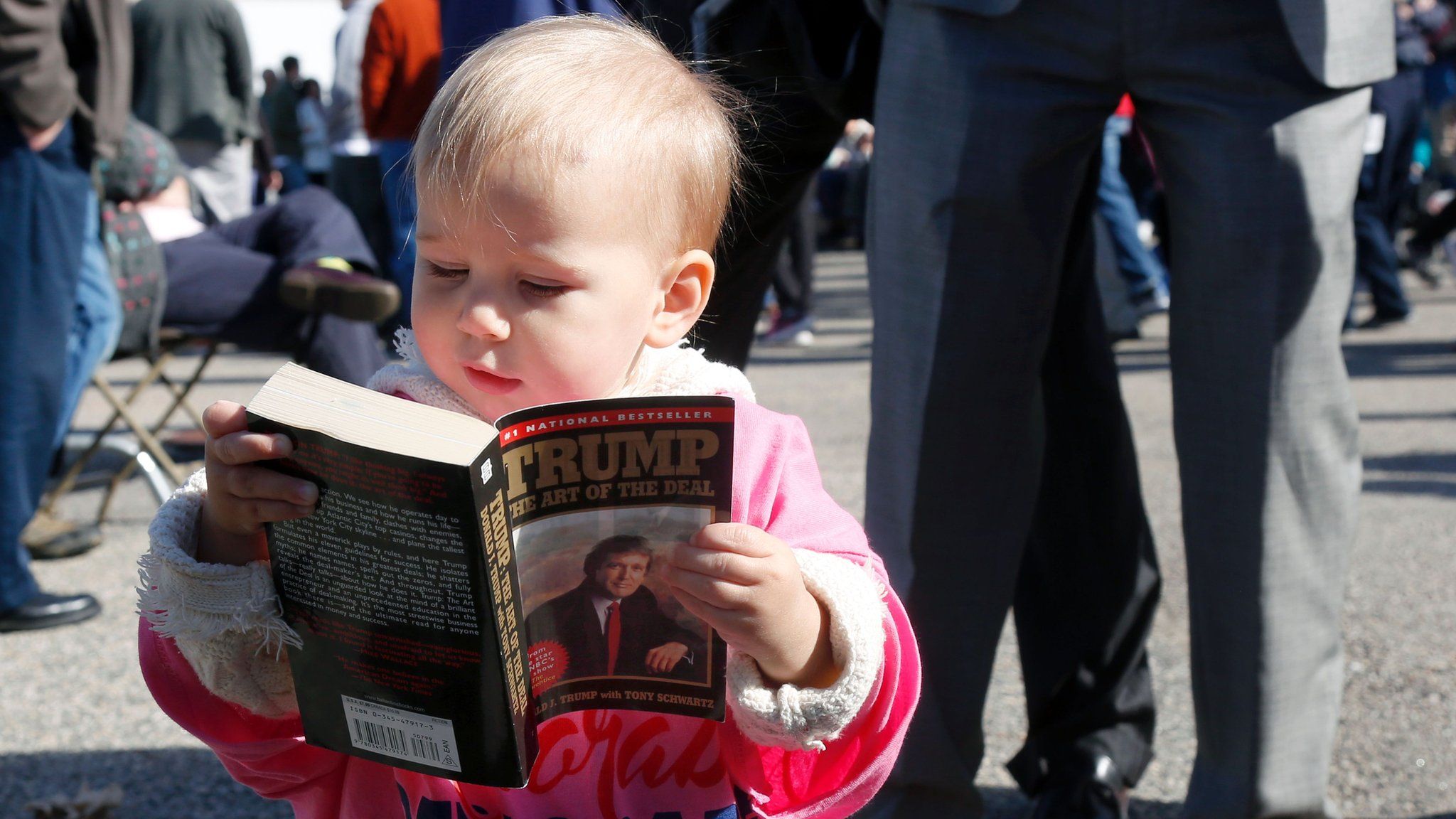 Grace Mahoney, 16 months, looks at a copy of 'The Art of the Deal' before the start of an event with Republican presidential candidate Donald Trump on October 15, 2016 in Portsmouth, New Hampshire.