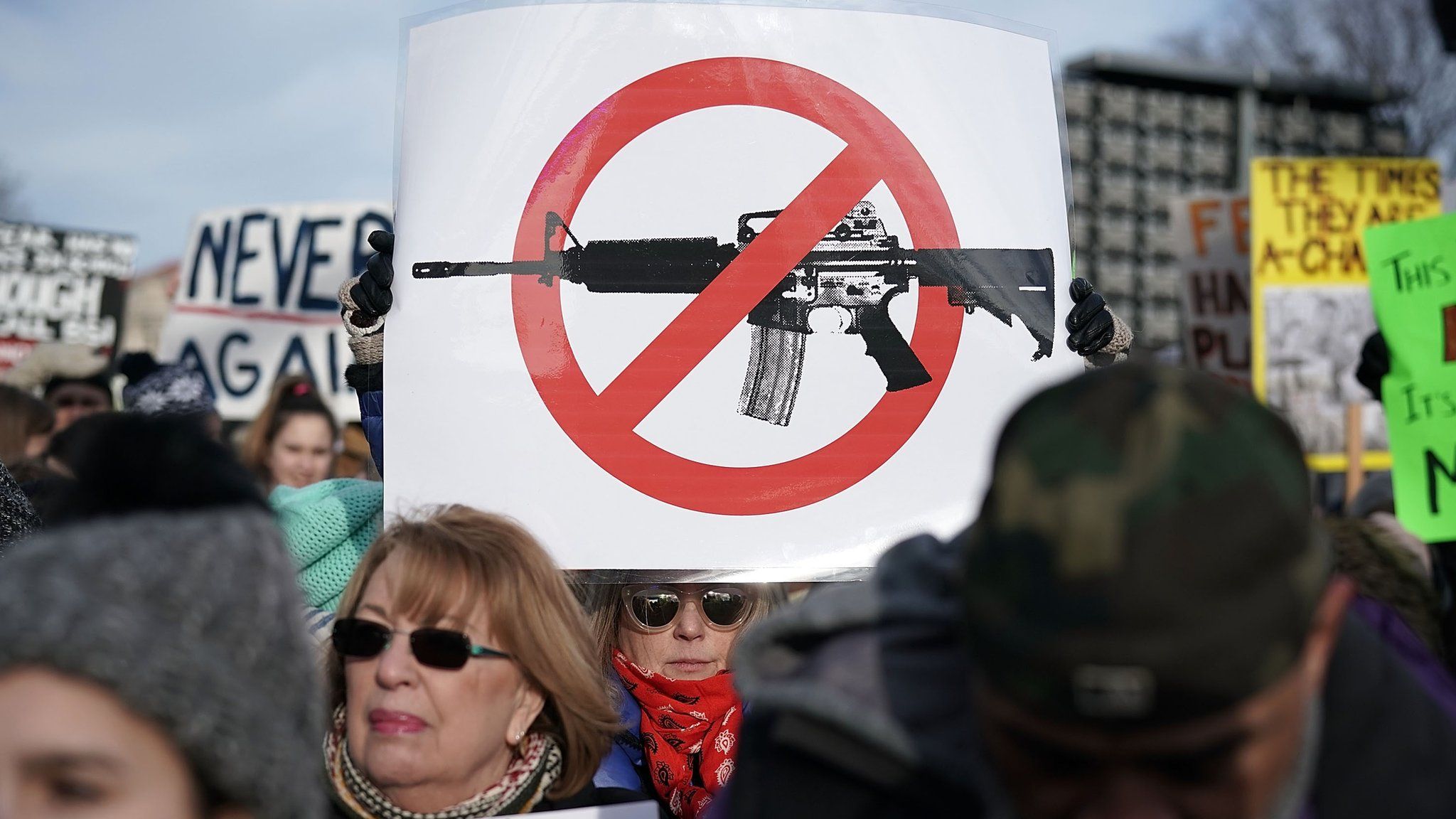 People hold signs as they wait for the beginning of the March for Our Lives rally on 24 March, 2018