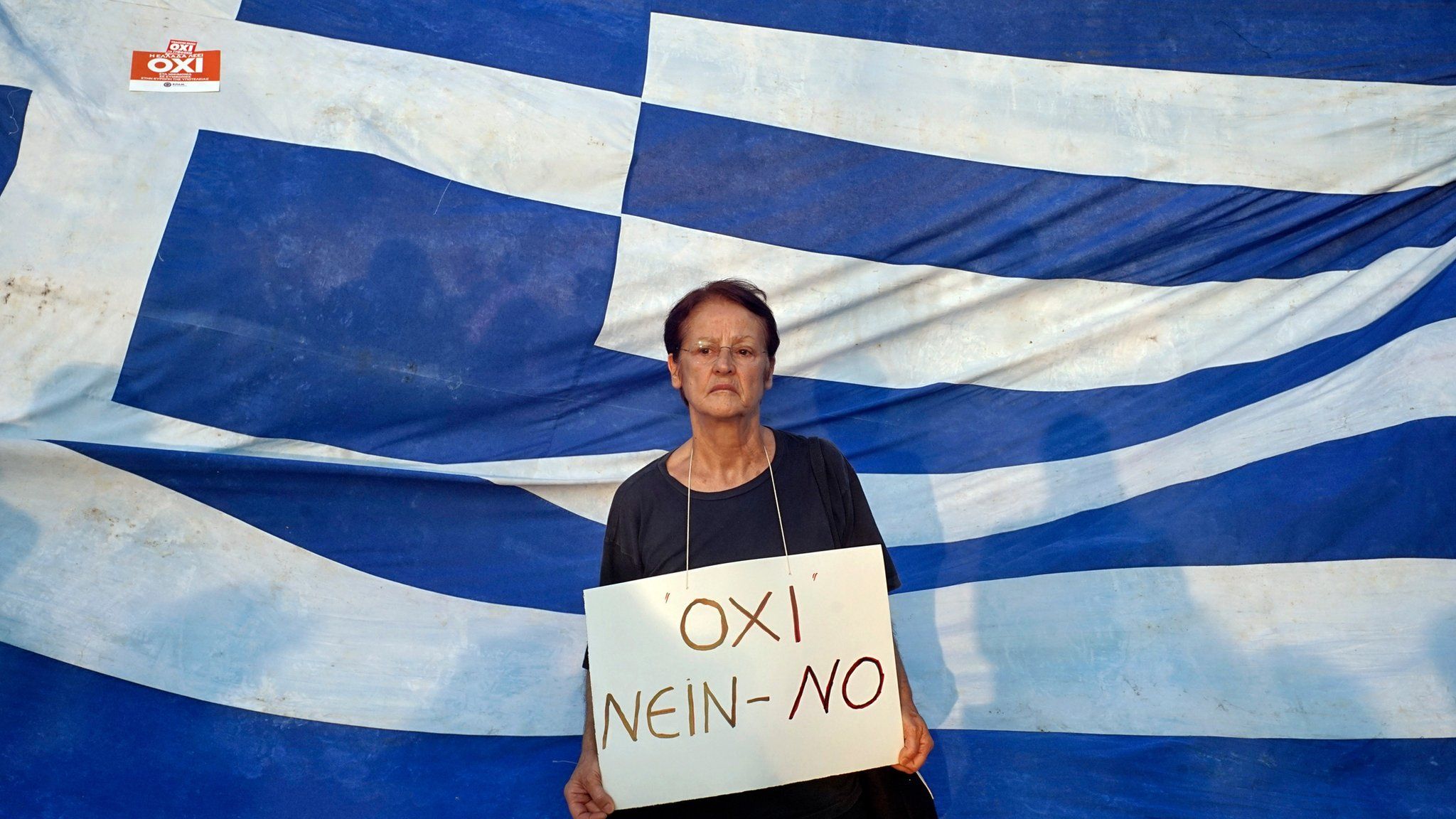 Woman protesting in front of the Greek flag