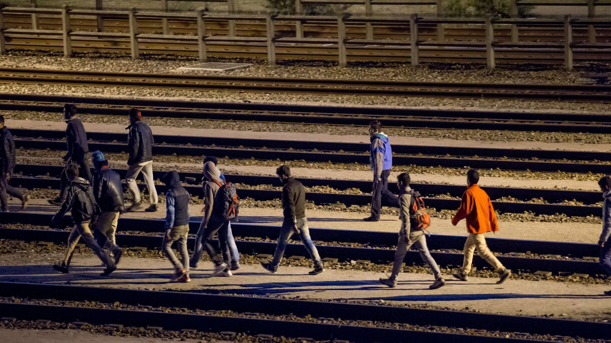 Migrants walk along rail tracks in Calais on 29 July 2015