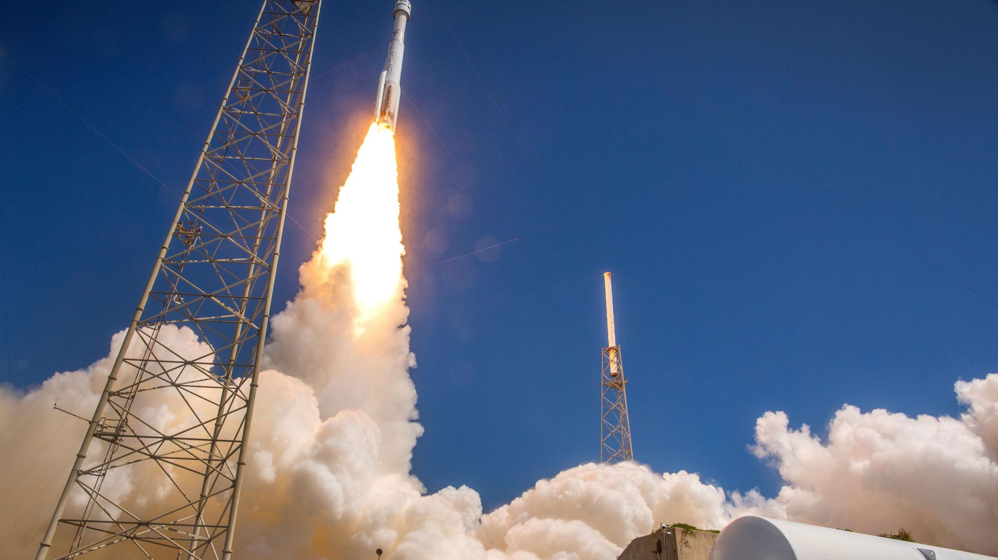 A rocket lifts off, making plumes of smoke on the ground