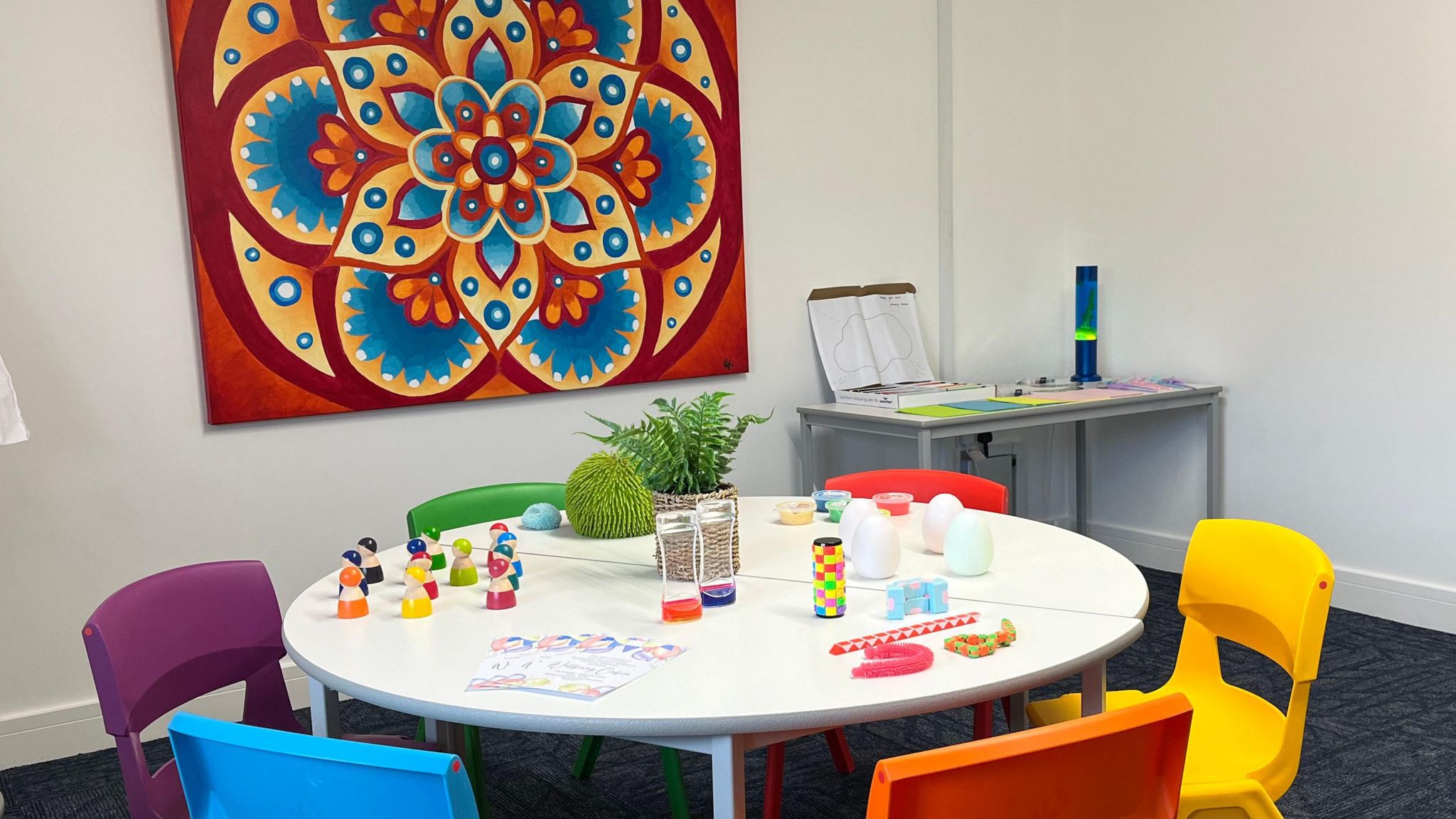 Table in one of the rooms of the new wellbeing hub with toys on it and brightly coloured chairs