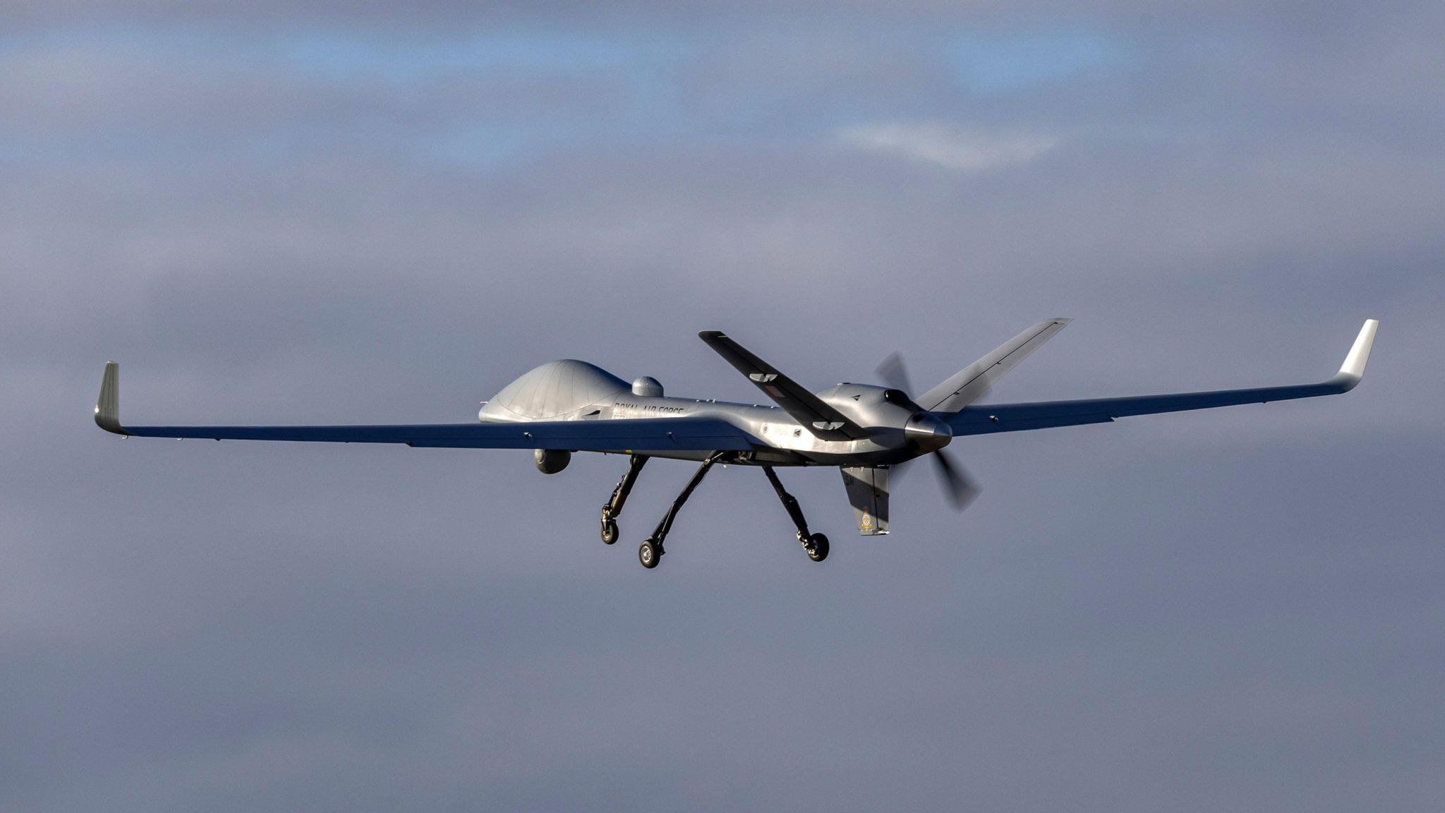 A remotely operated surveillance drone mid-flight at RAF Waddington on an cloudy day
