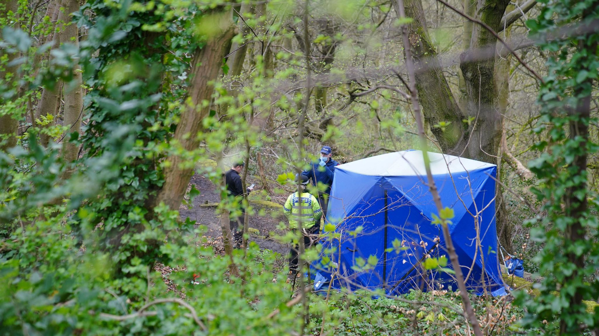 Police officers by a forensic tent at Kersal Dale