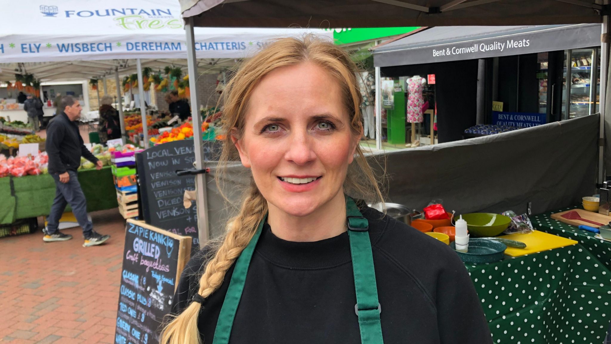 Justyna Vail in a black jumper standing in front of a market stall 