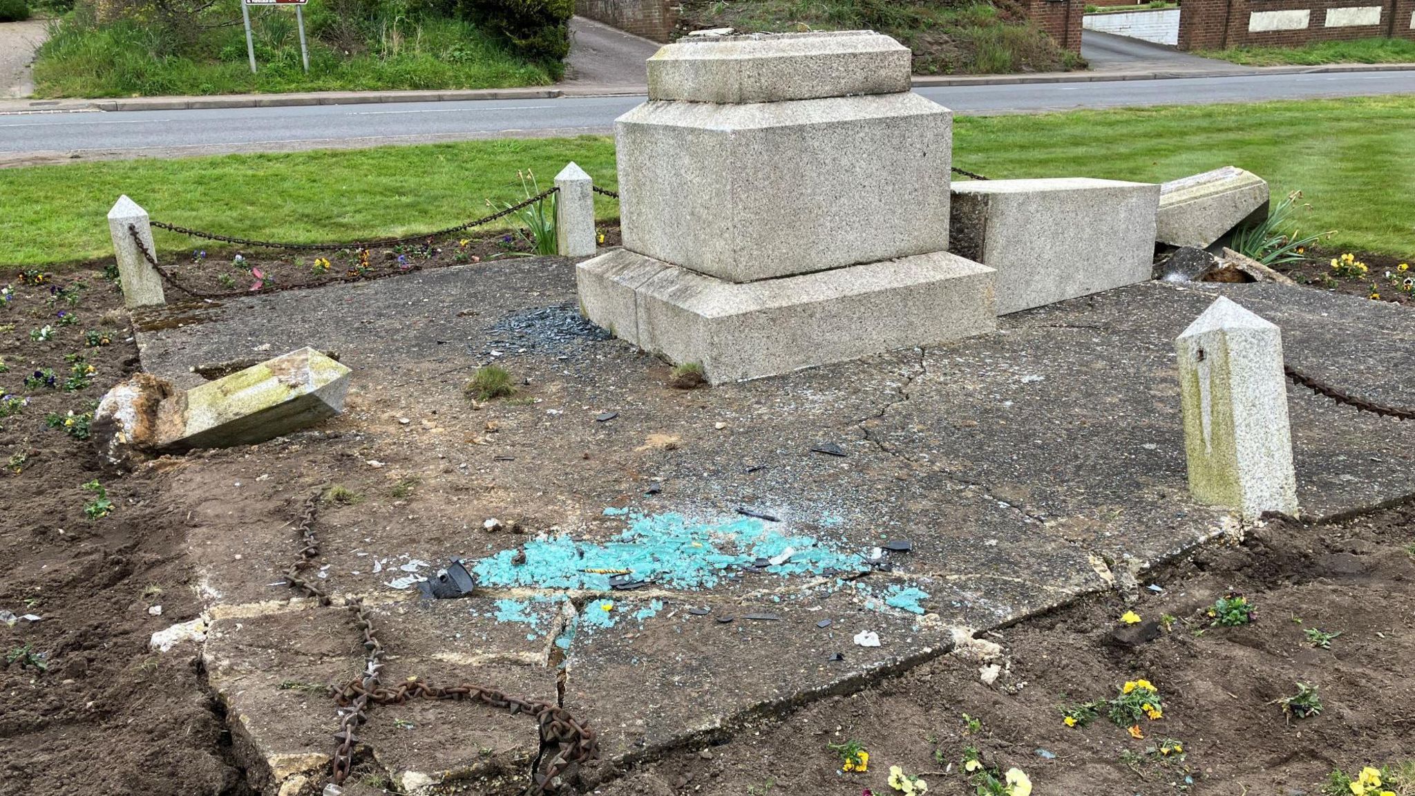 The damaged memorial with broken glass in front of it
