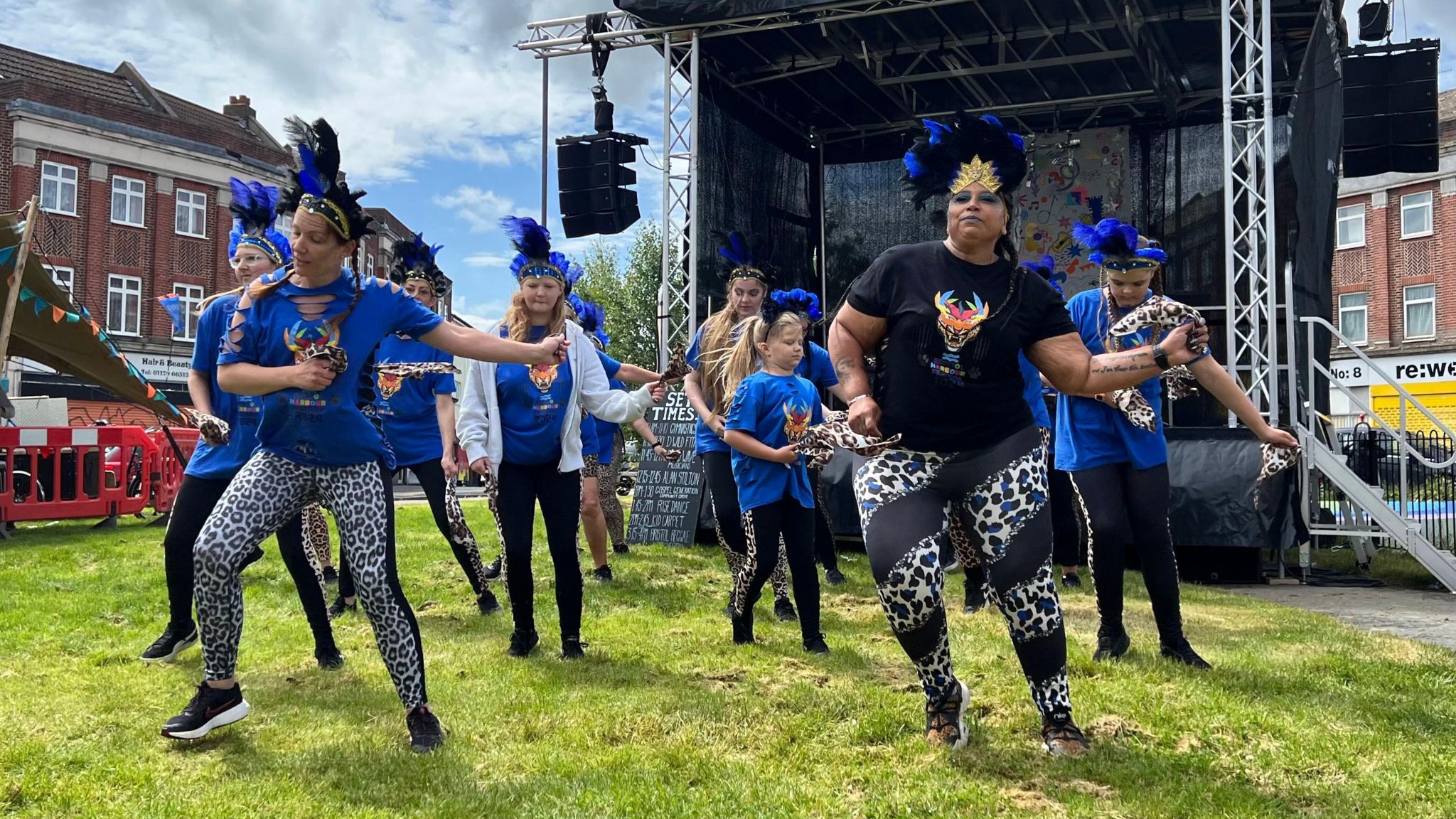A group of dancers in blue tops and printed trousers dance during the Knowle West community day