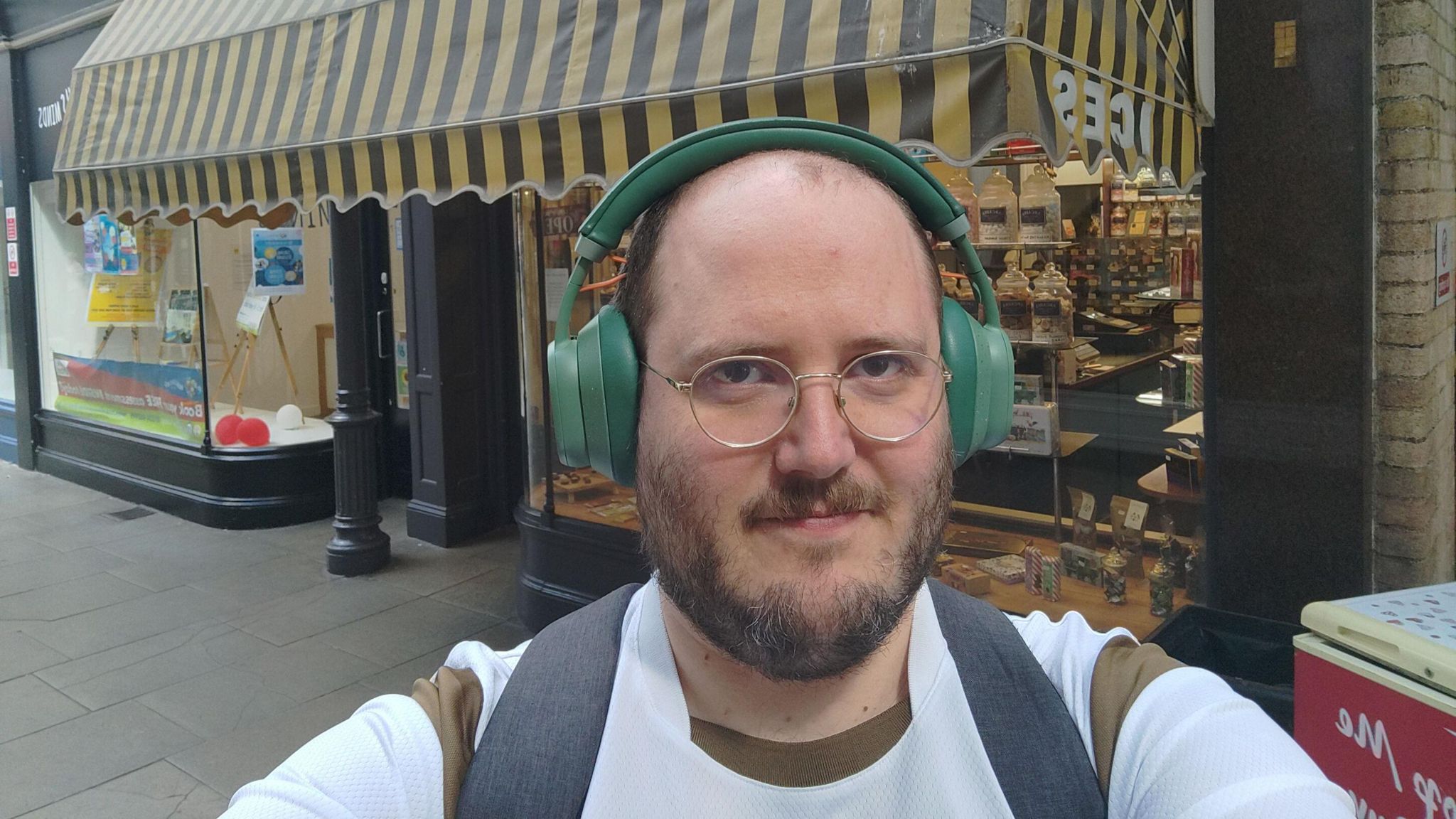Alex Levene wearing headphones in front of a sweet shop