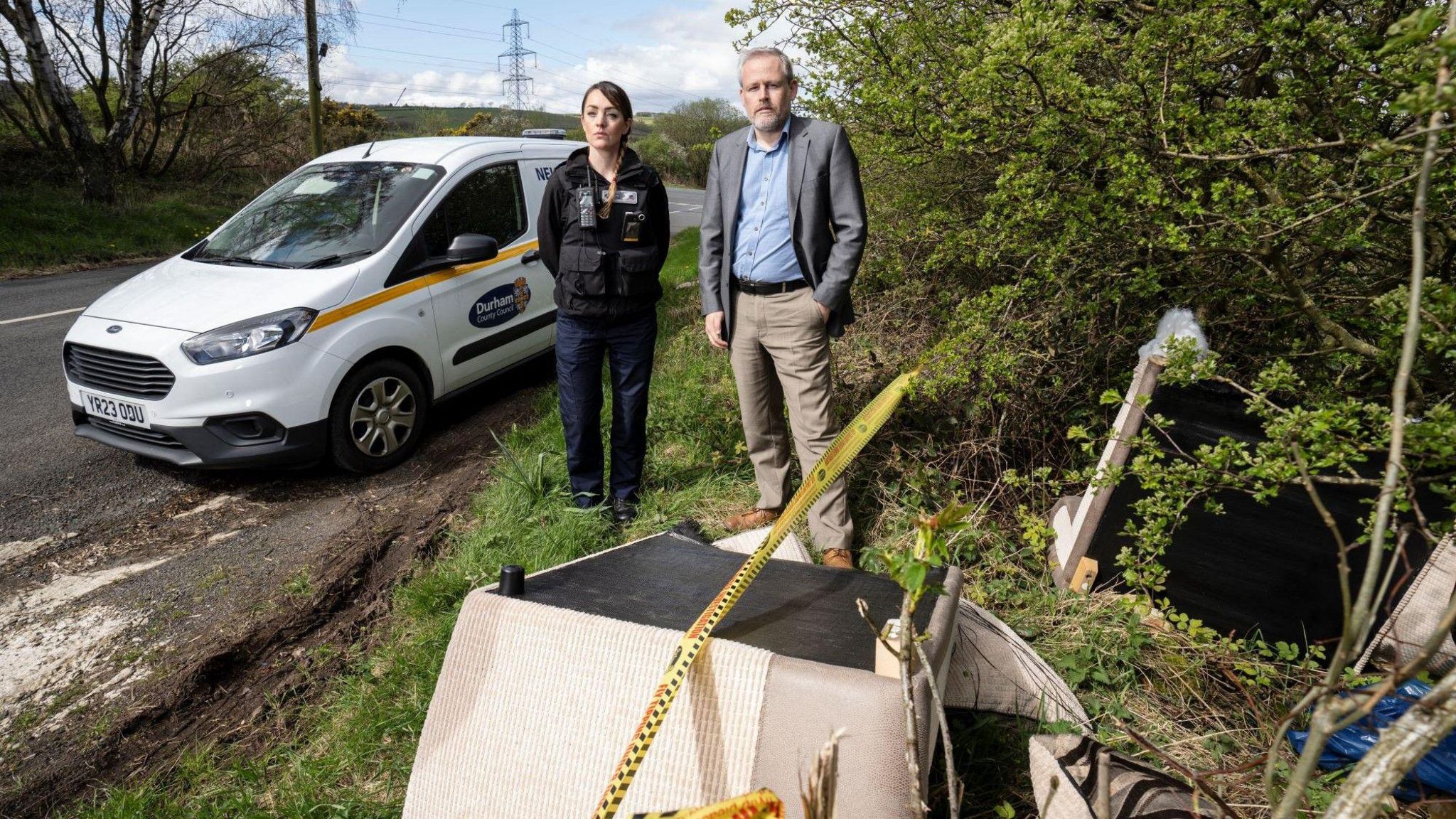 Cllr Mark Wilkes, Durham County Council’s Cabinet member for neighbourhoods and climate change, is pictured with neighbourhood warden Claire Liddle looking at a fly-tip in the Esh area with a Durham County Council van behind them 