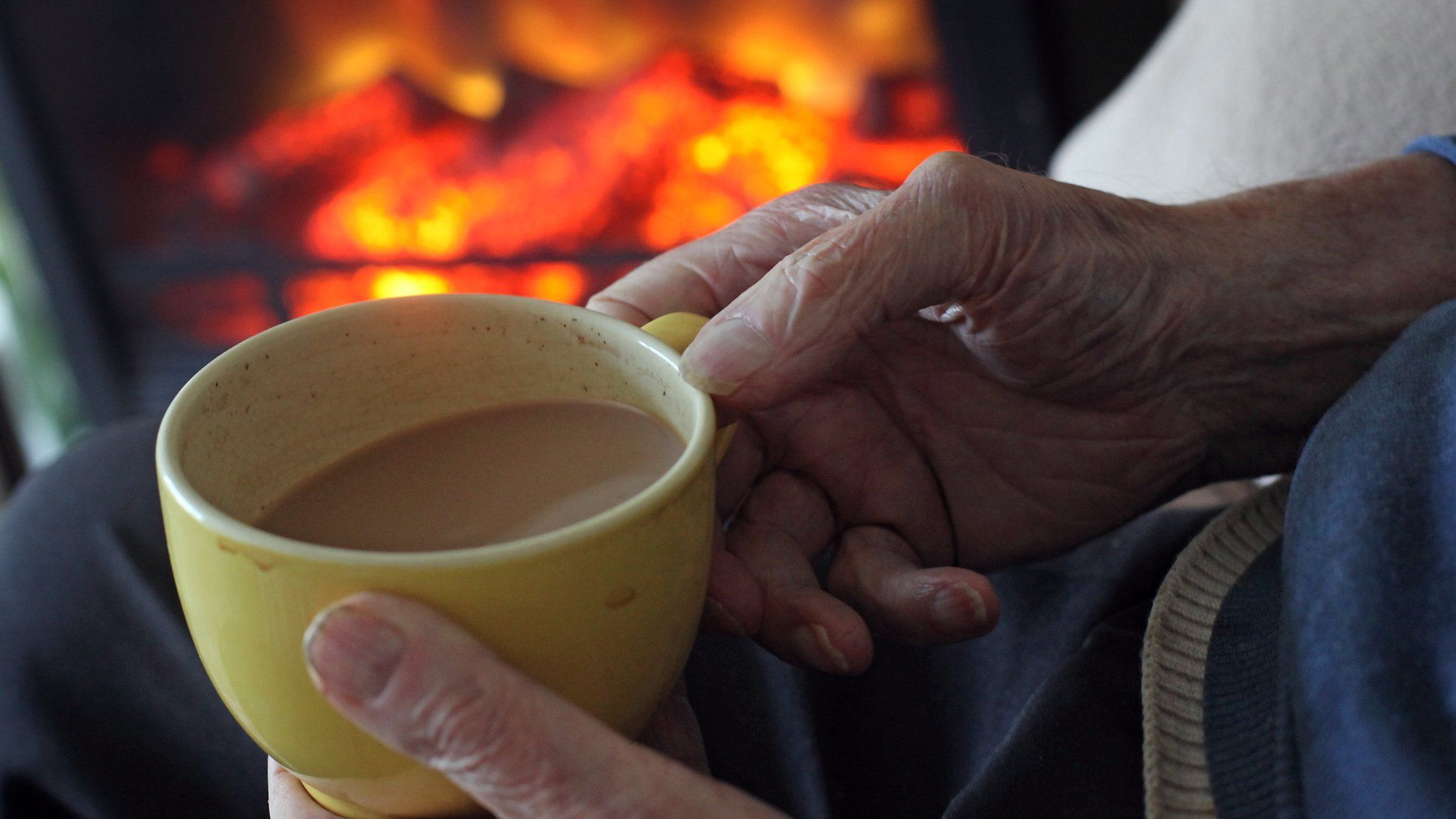 old person holds cup of tea