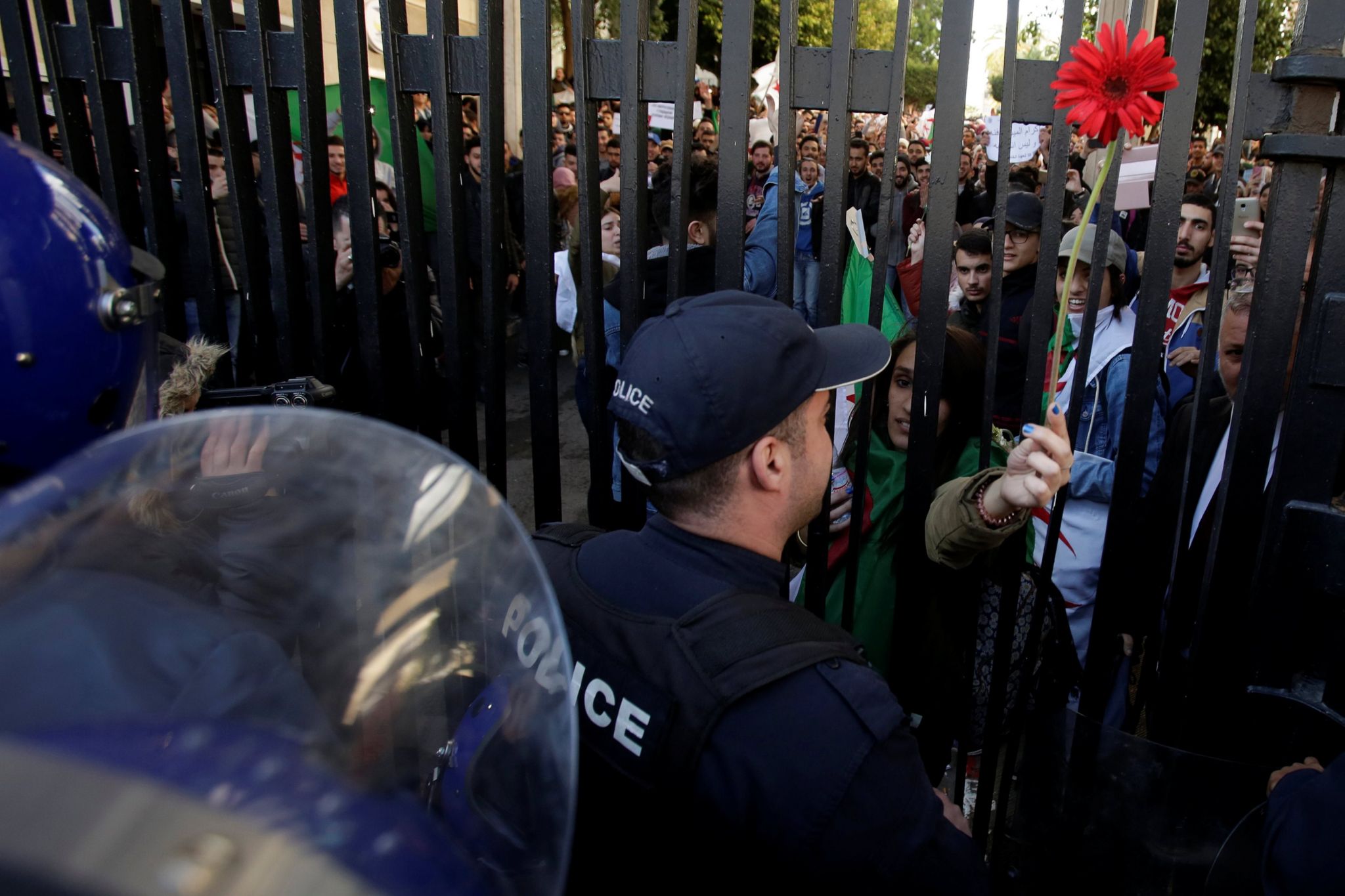 A student offers a flower to police while she protests with others inside a university campus against the fifth term of Abdelaziz Bouteflika in Algiers