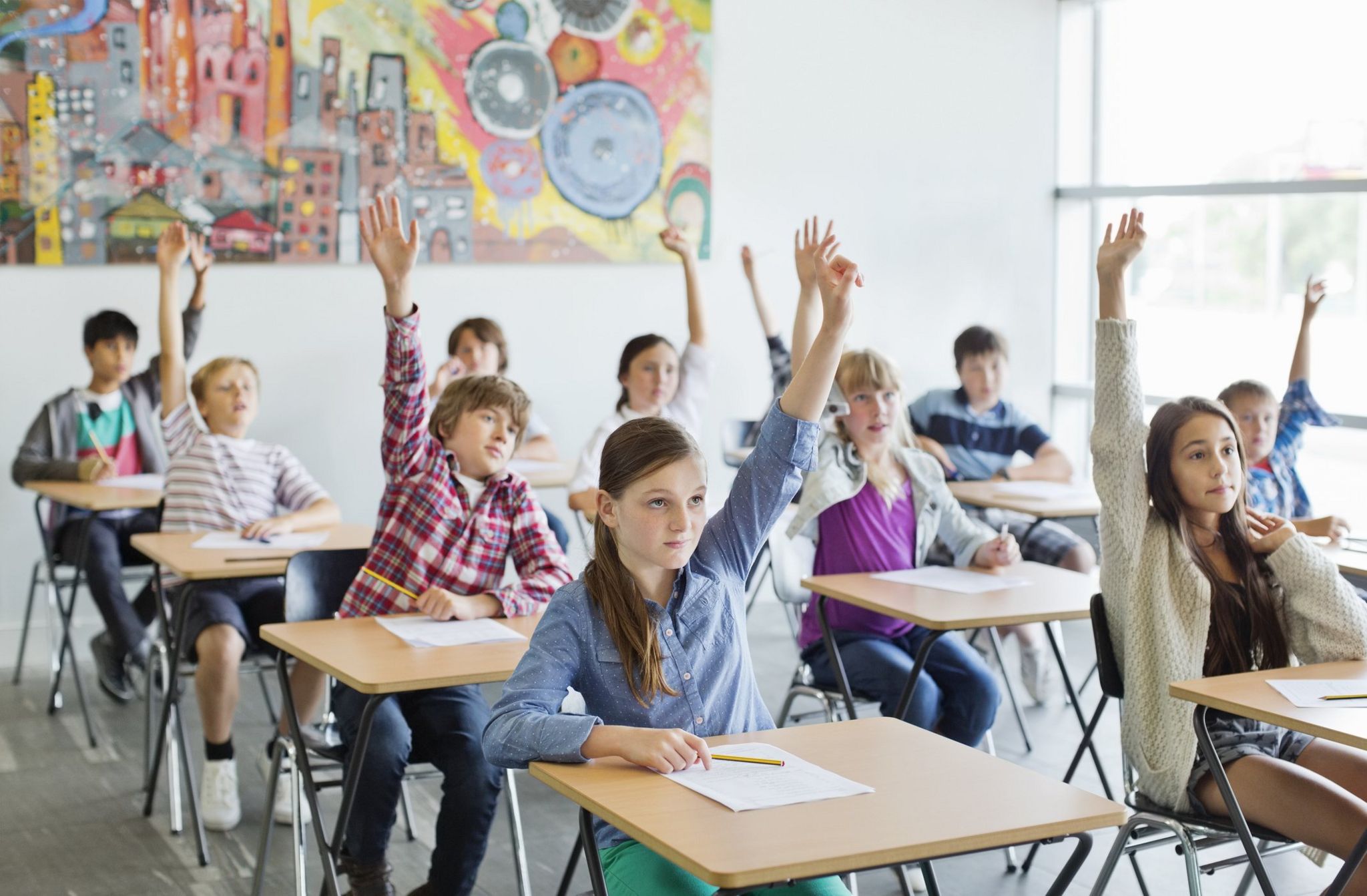 Children in a classroom put their hands up