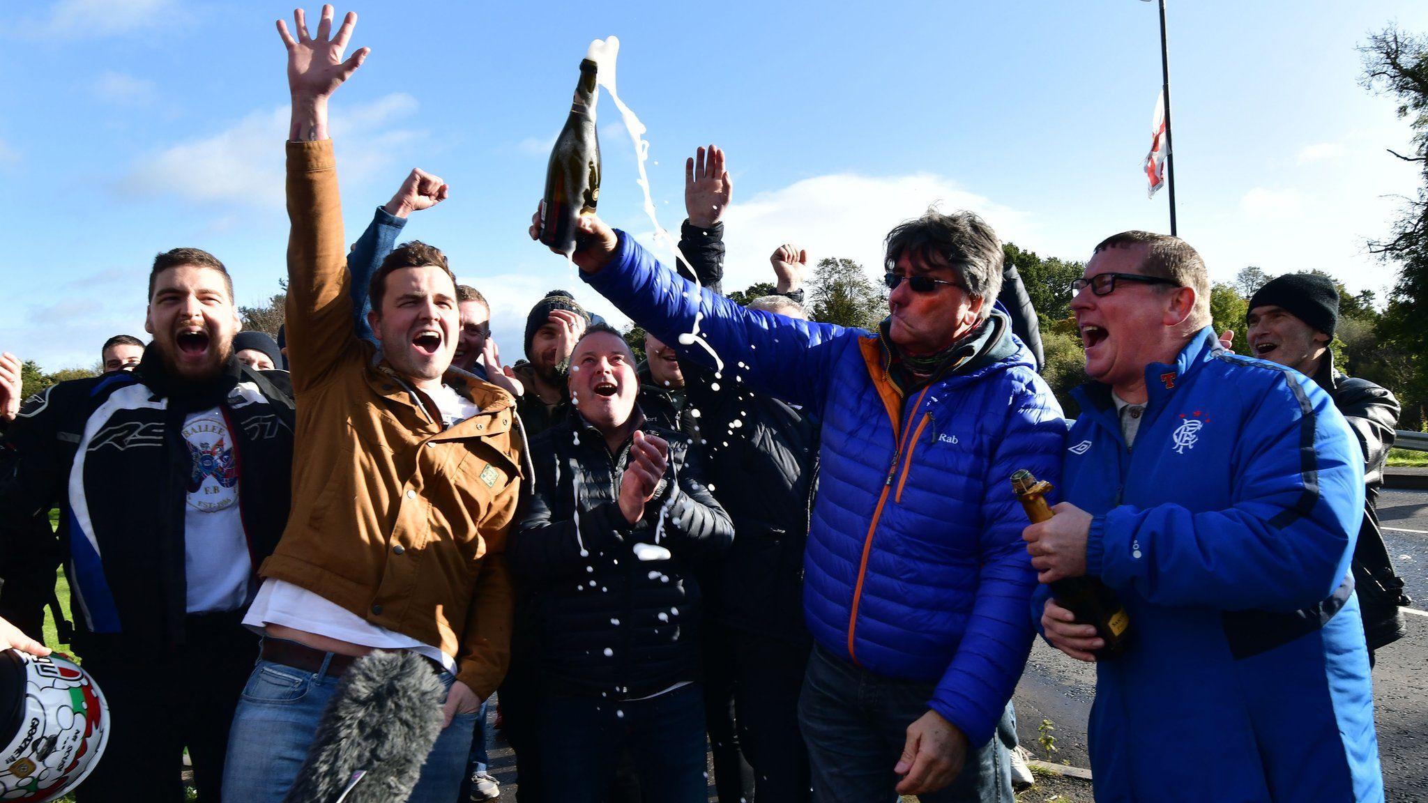 Wrightbus workers celebrate with a bottle of champagne outside the factory