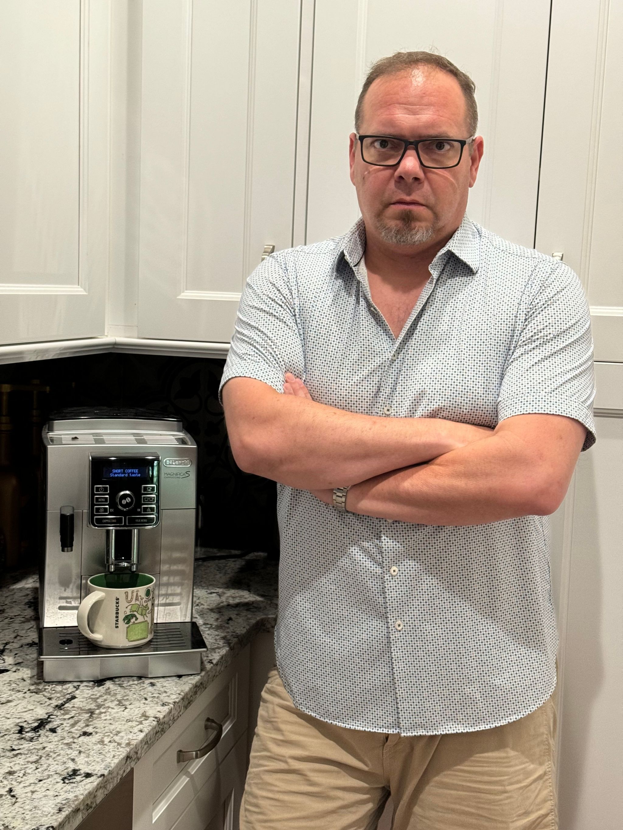 Andrew Buckley standing with arms crossed in his kitchen next to his coffee machine