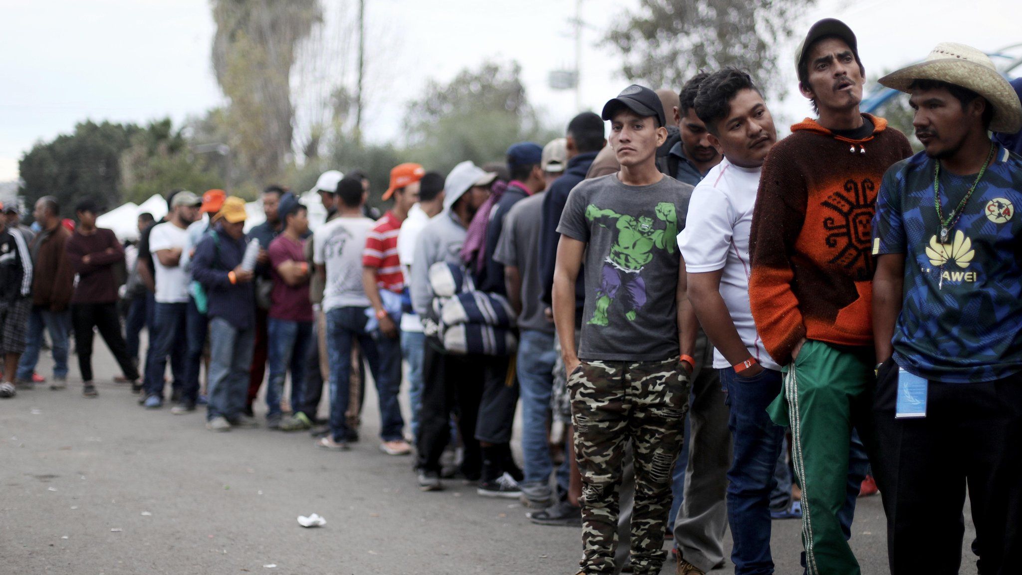 Migrants wait for dinner outside a shelter in Tijuana