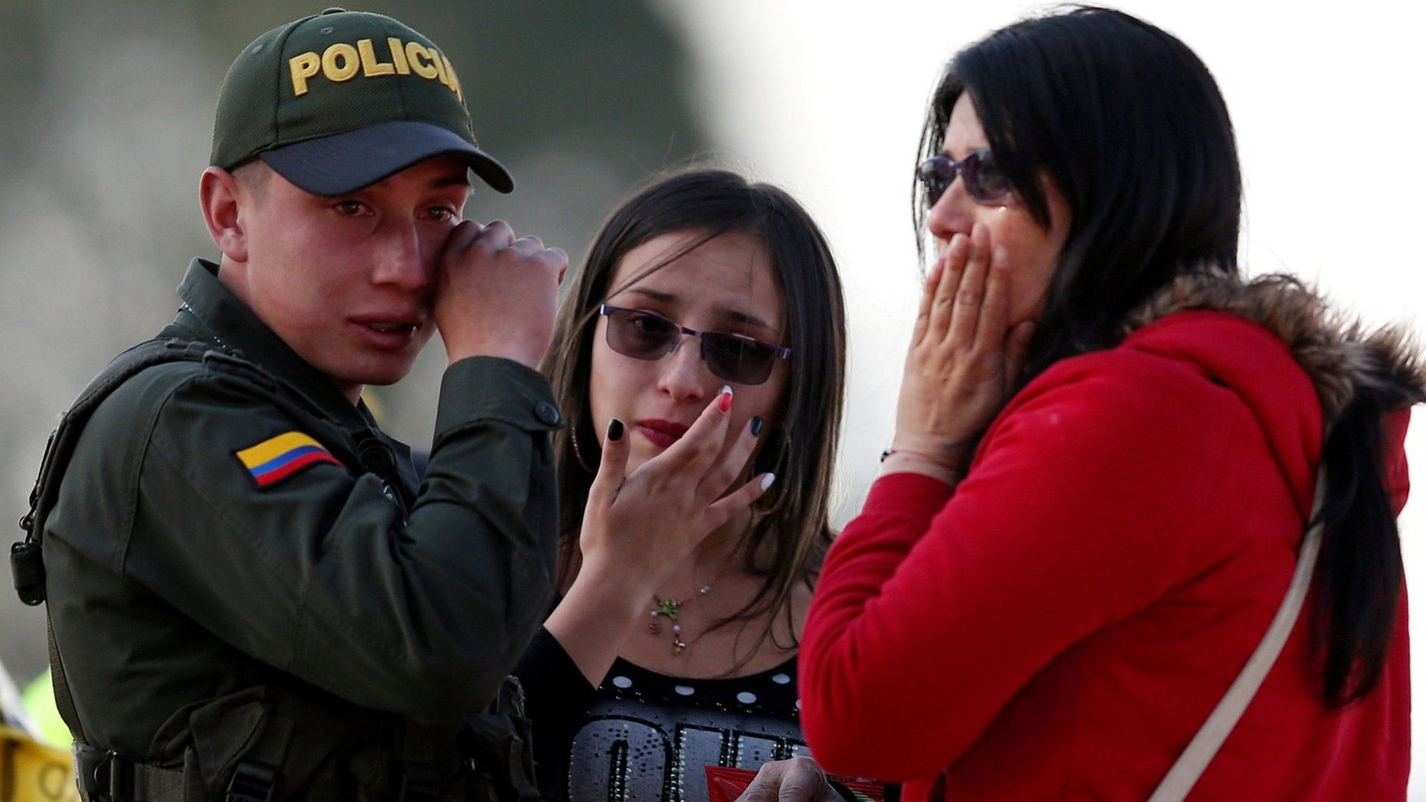 A police officer and two women wipe their tears close to the scene where a car bomb exploded