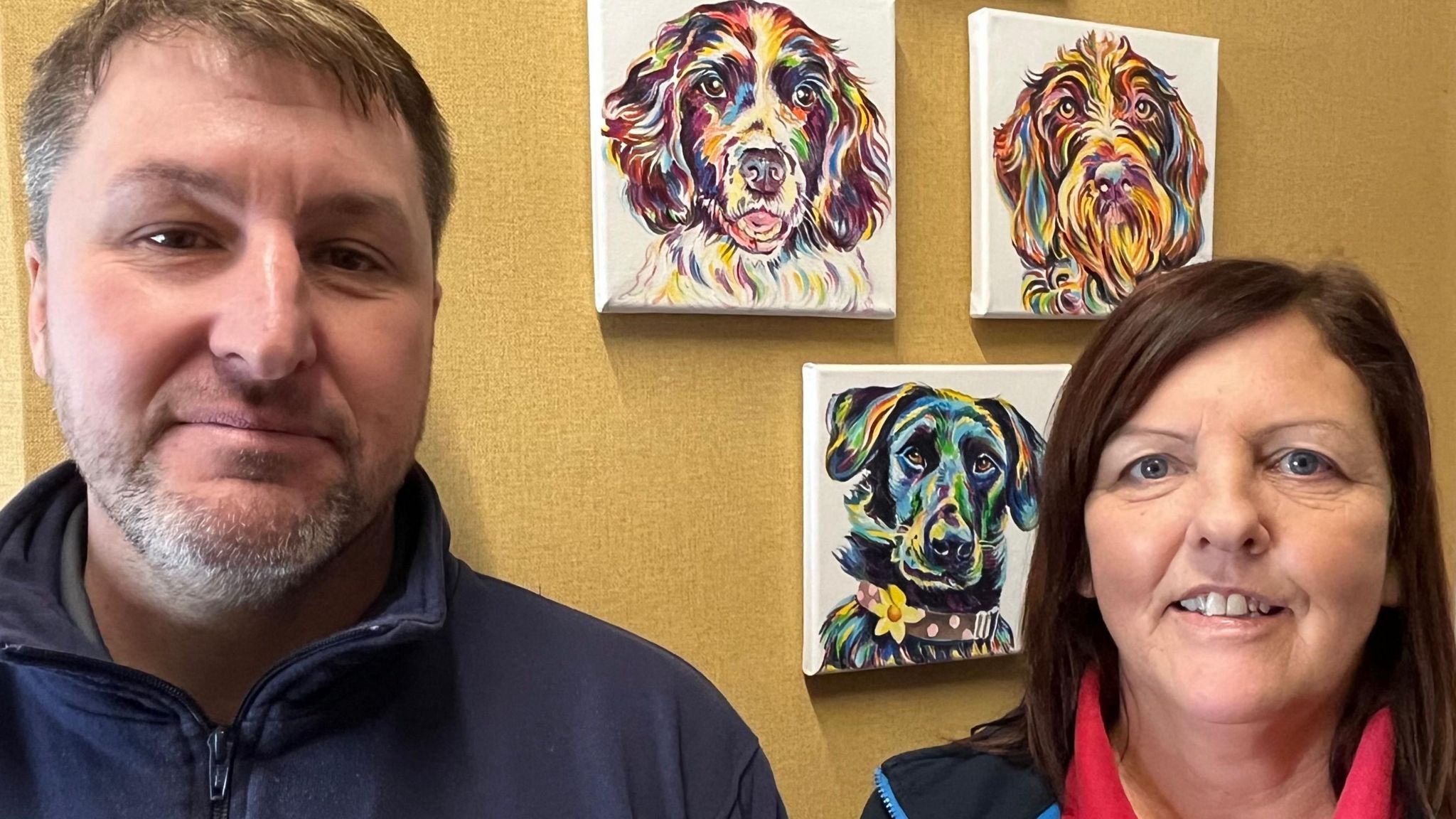 Darren Bates and Wendy Stone with dog portraits behind them