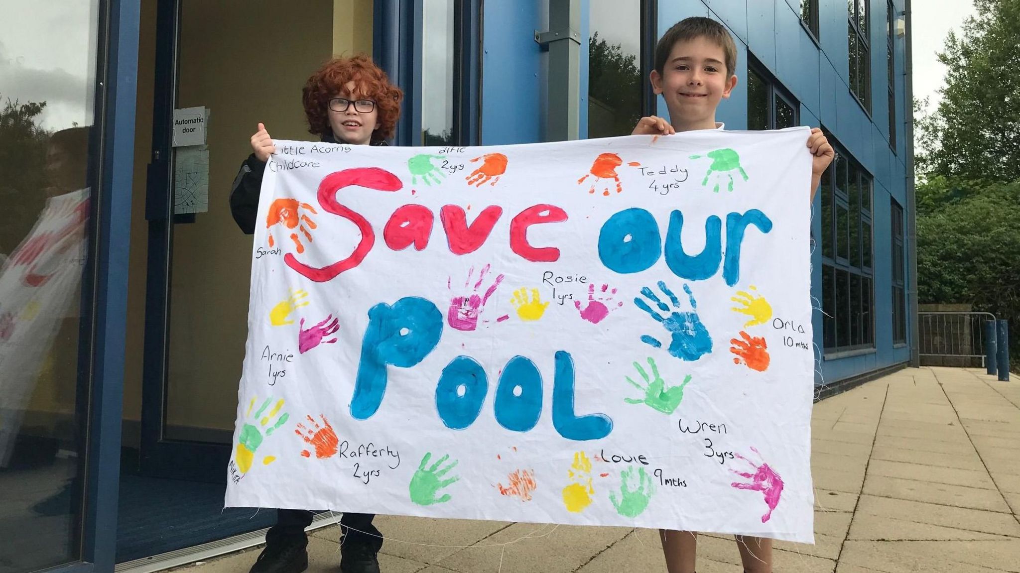 Two children hold up a 'Save Our Pool' sign