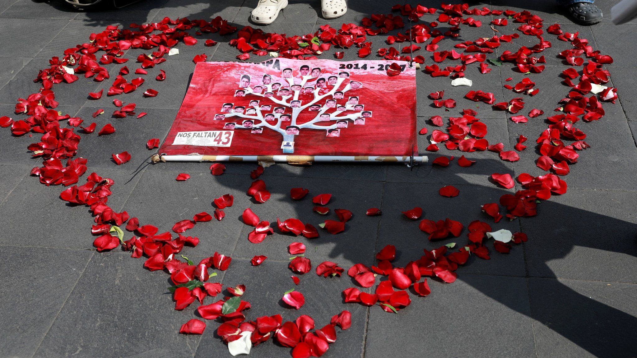 Pictures of the 43 missing students are displayed inside a heart shape made out of rose petals on the pavement in Mexico City