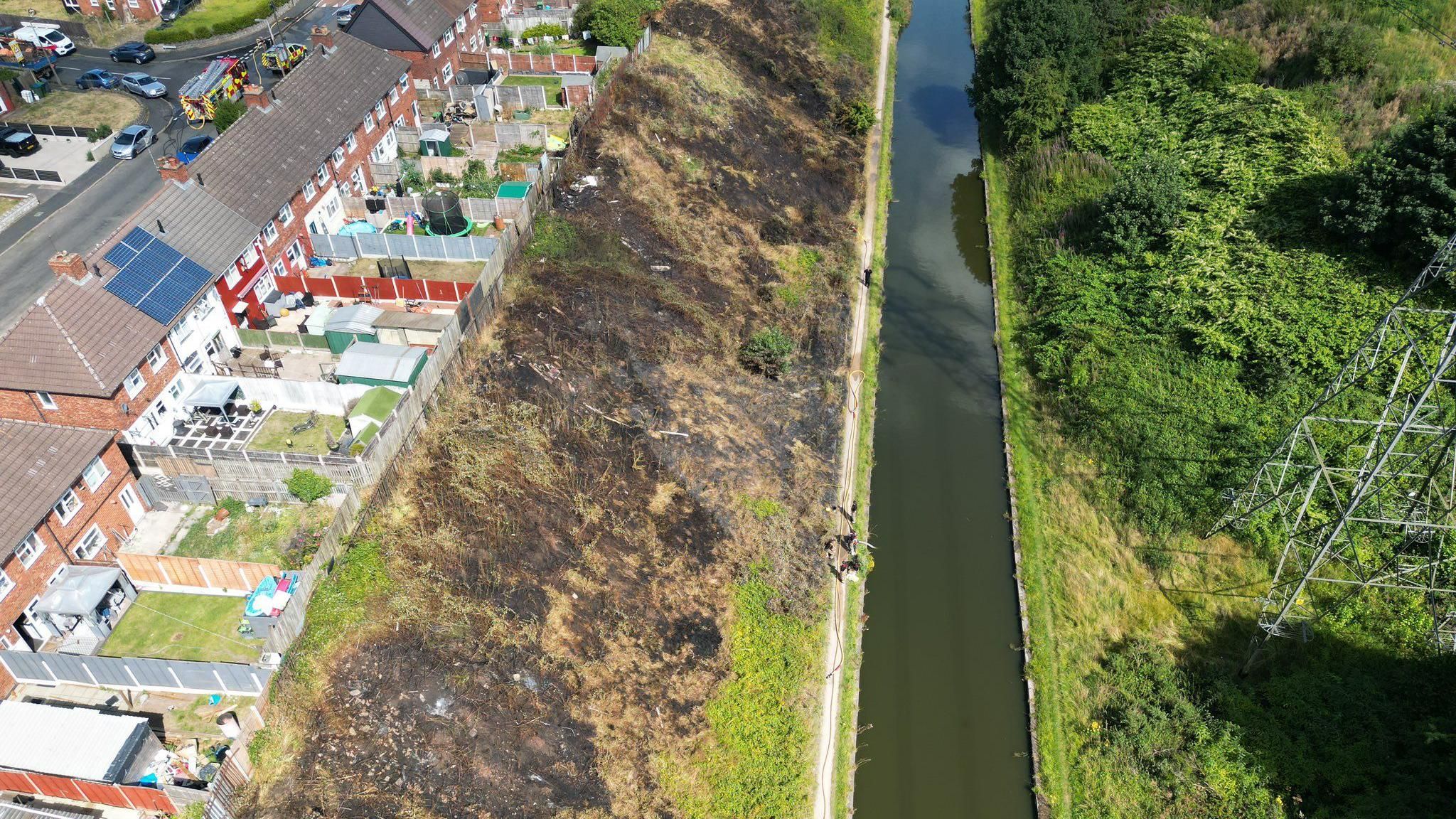 Drone picture of scorched earth alongside the Tame Valley Canal, backing on to a row of gardens.