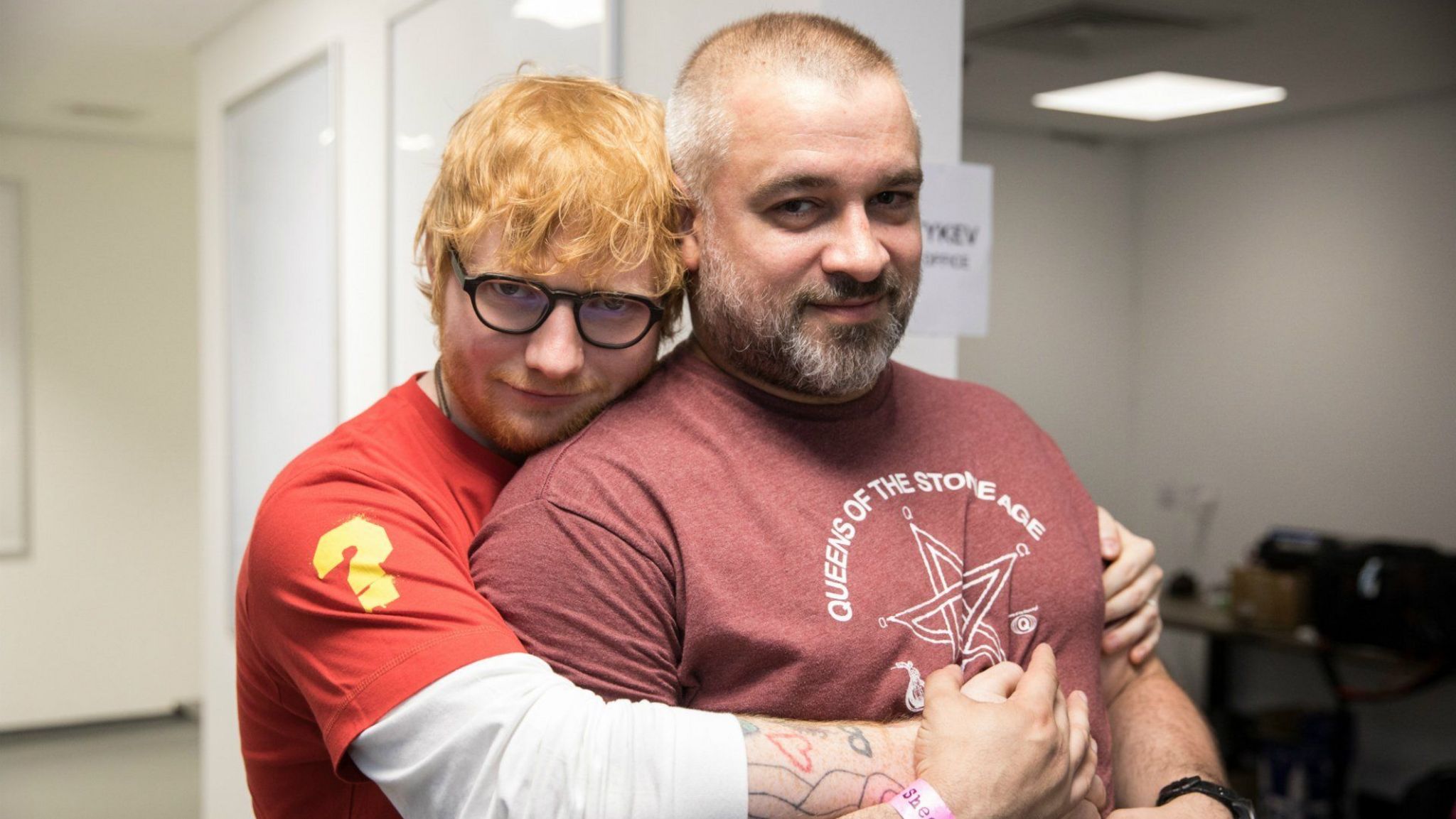 Ed Sheeran hugging his manager Stuart Camp from behind