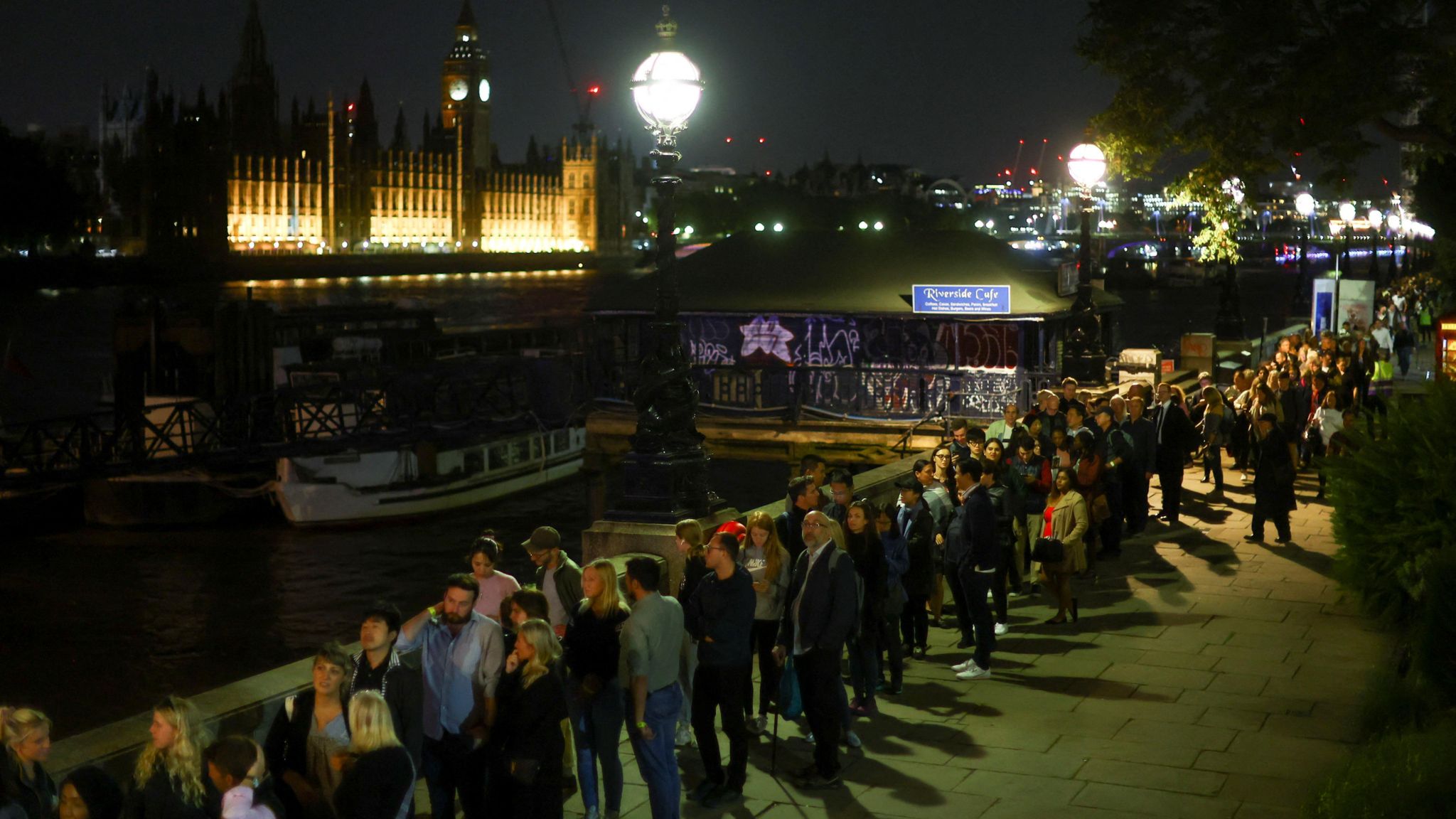 A queue of people waiting at night alongside the River Thames to pay their tributes to Queen Elizabeth II