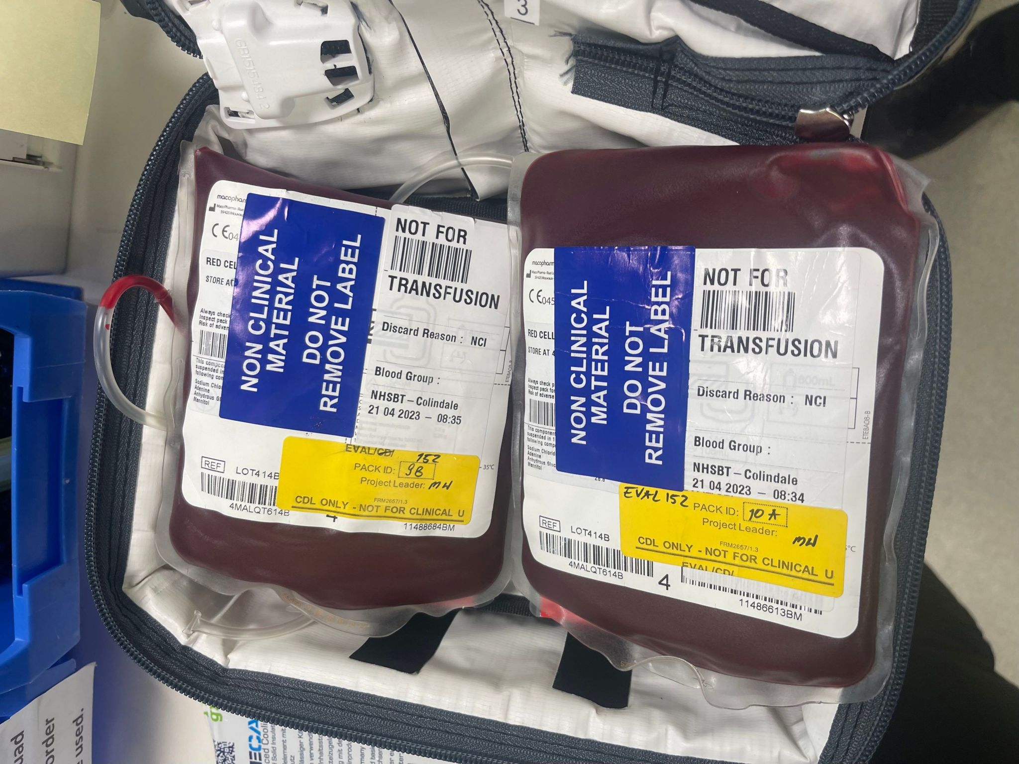 An image of a unzipped bag showing two packs of blood with a sign on them saying non clinical material not for transfusion 