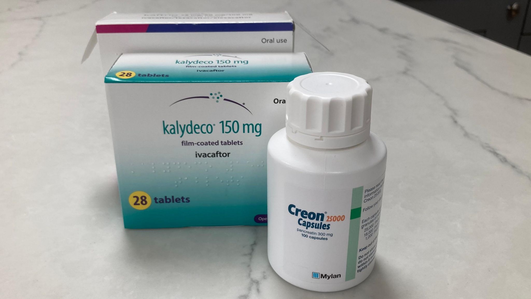 A bottle of Creon tablets and box of Kalydeco tablets