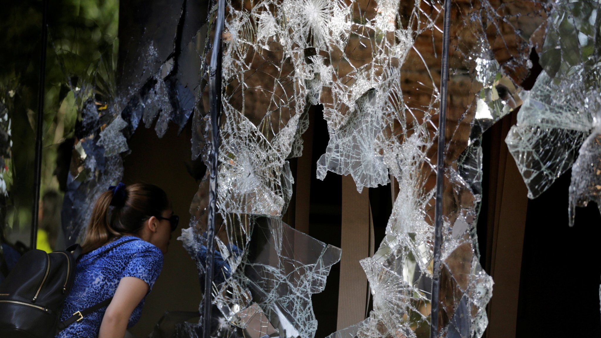 A woman looks through damaged windows of the Congress building a day after a demonstration against a possible change in law to allow for presidential re-election in Asuncion, Paraguay, April 1, 2017