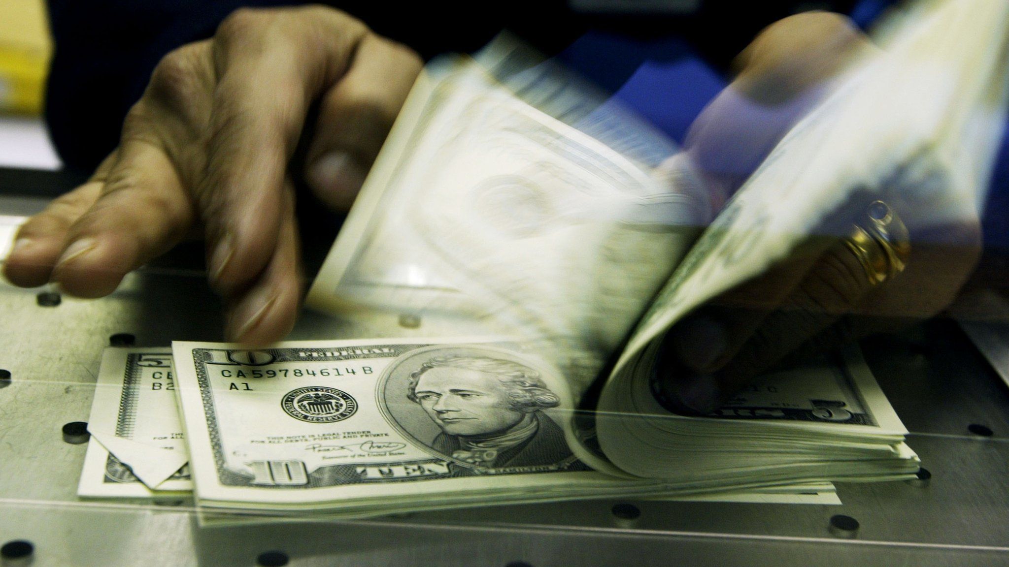 A cashier counts U.S. Dollars