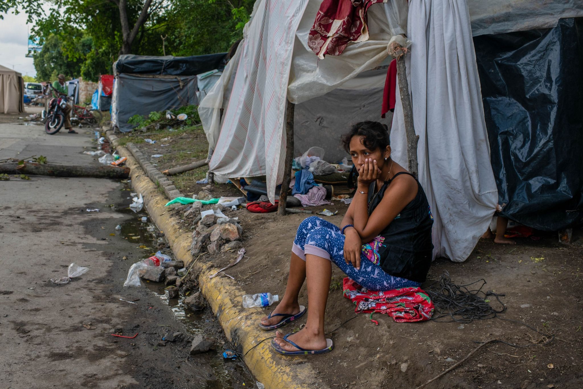 Susan Jesenia Aguilar sits in front of the makeshift tent where she has been living since her home flooded.