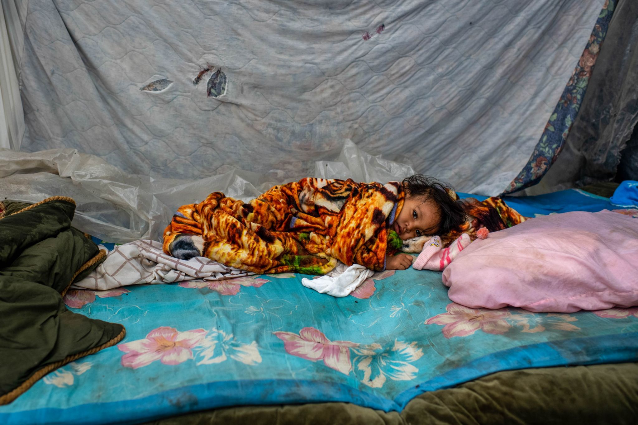 A baby lies in a makeshift shelter by a highway on the outskirts of San Pedro Sula
