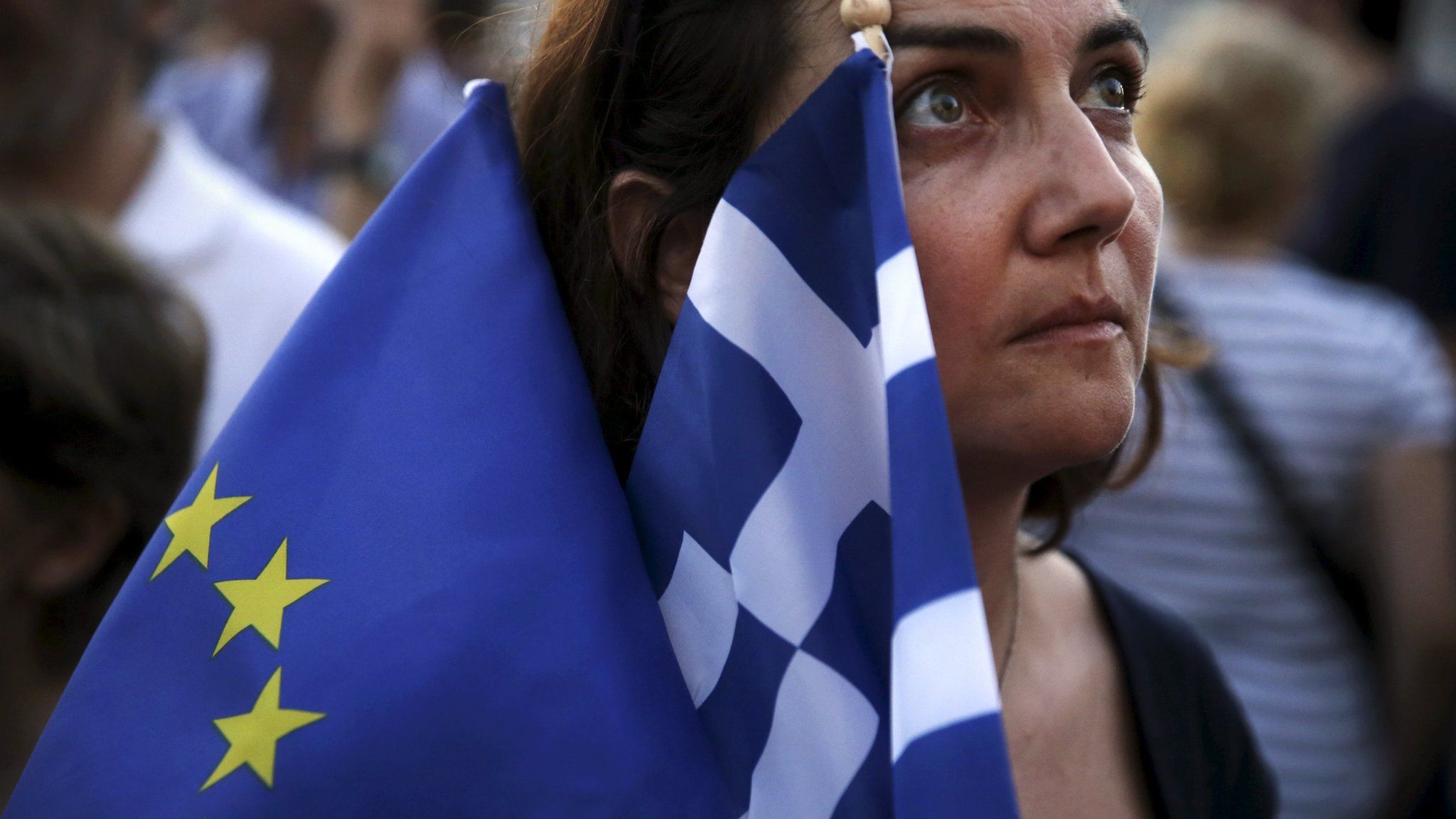 A pro-Euro protester holds a European Union and a Greek national flag during a rally in front of the parliament building in Athens, Greece, July 9, 2015