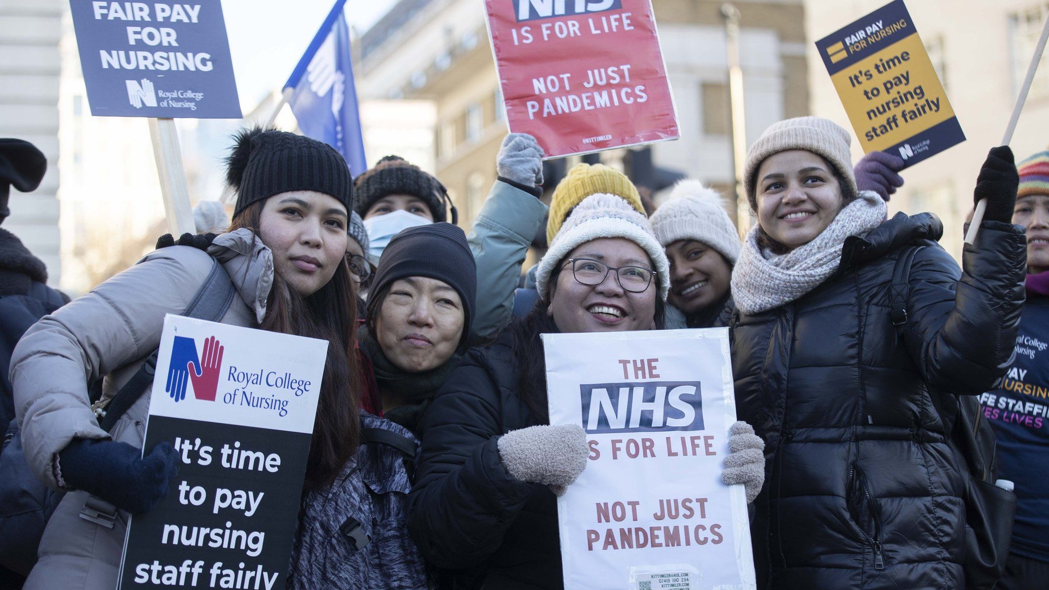 Striking nurses holding up picket signs