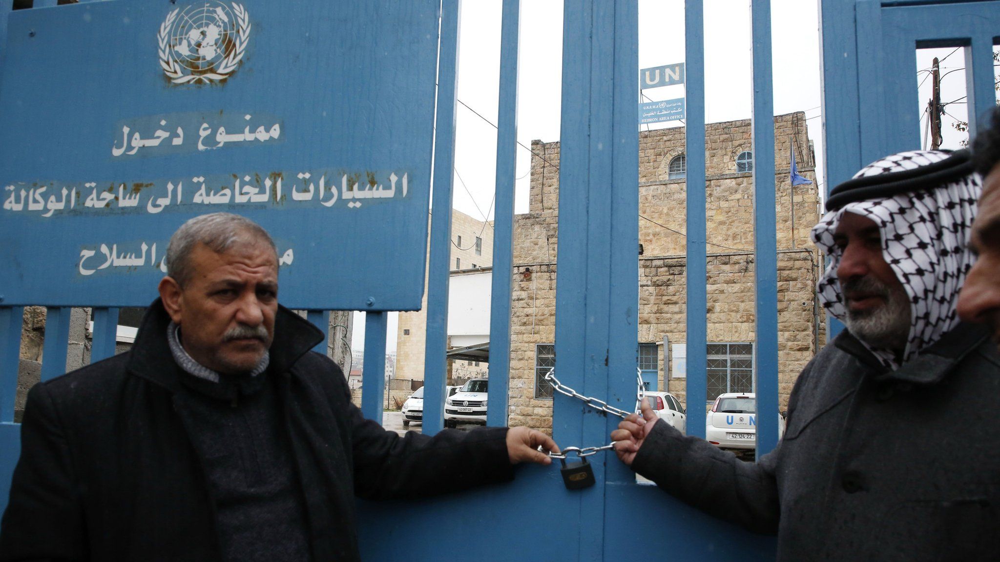 Palestinian men symbolically lock shut the gates of an Unrwa office in the West Bank city of Hebron on 17 January 2018