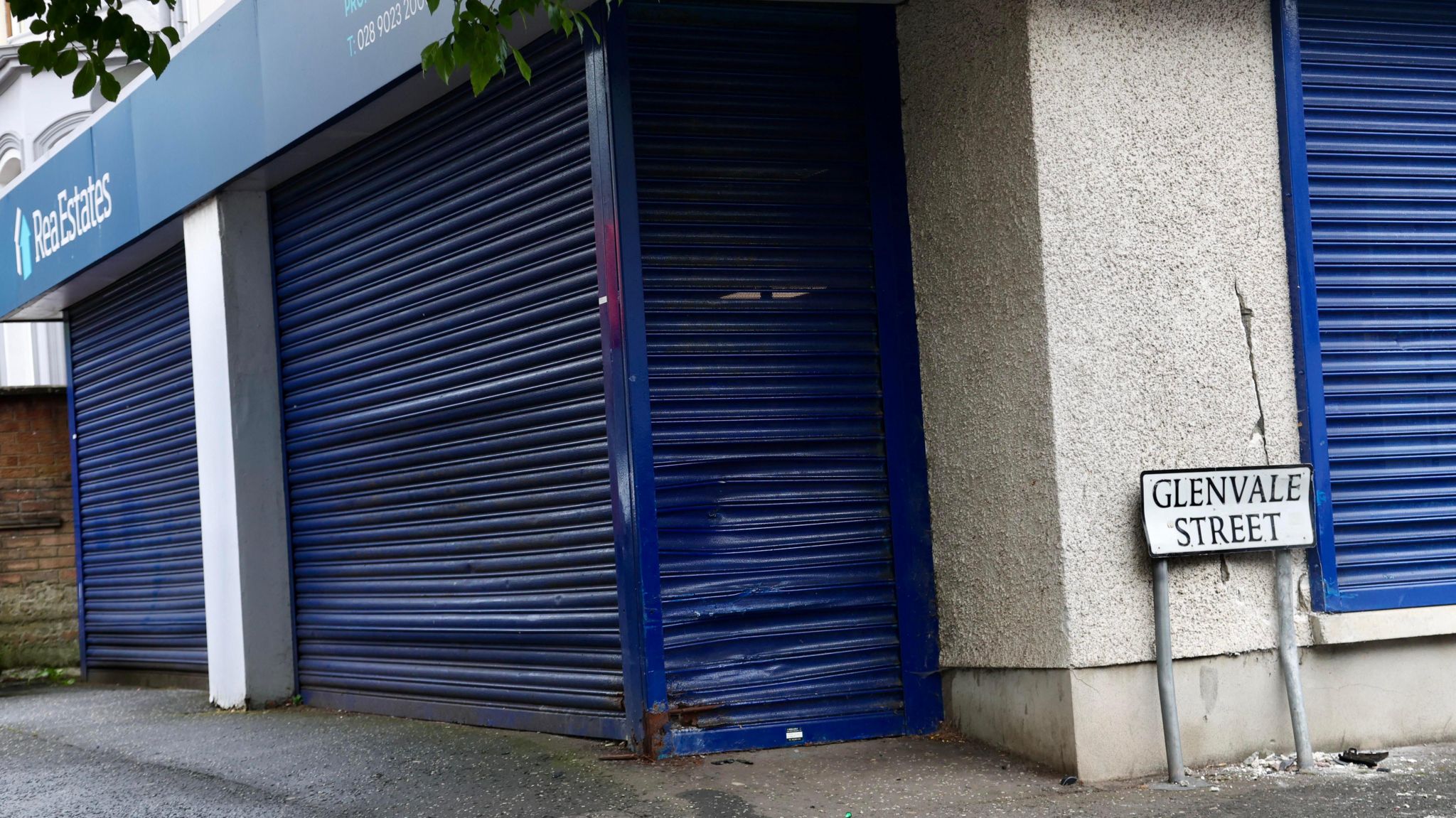 Blue shutters pulled down on an estate agents with minor damage.