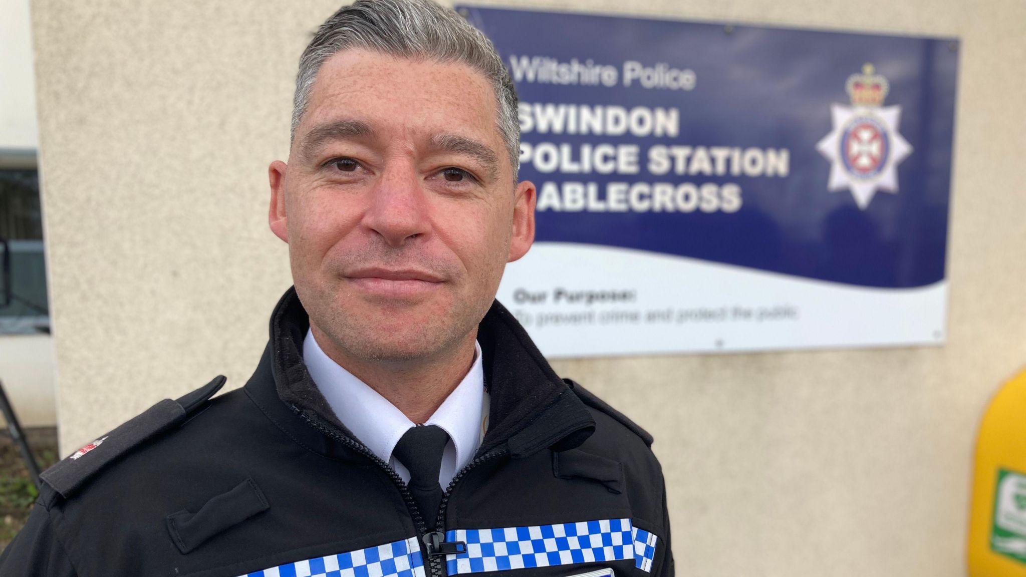 Police superintendent standing in front of the sign for Swindon Gablecross police station.