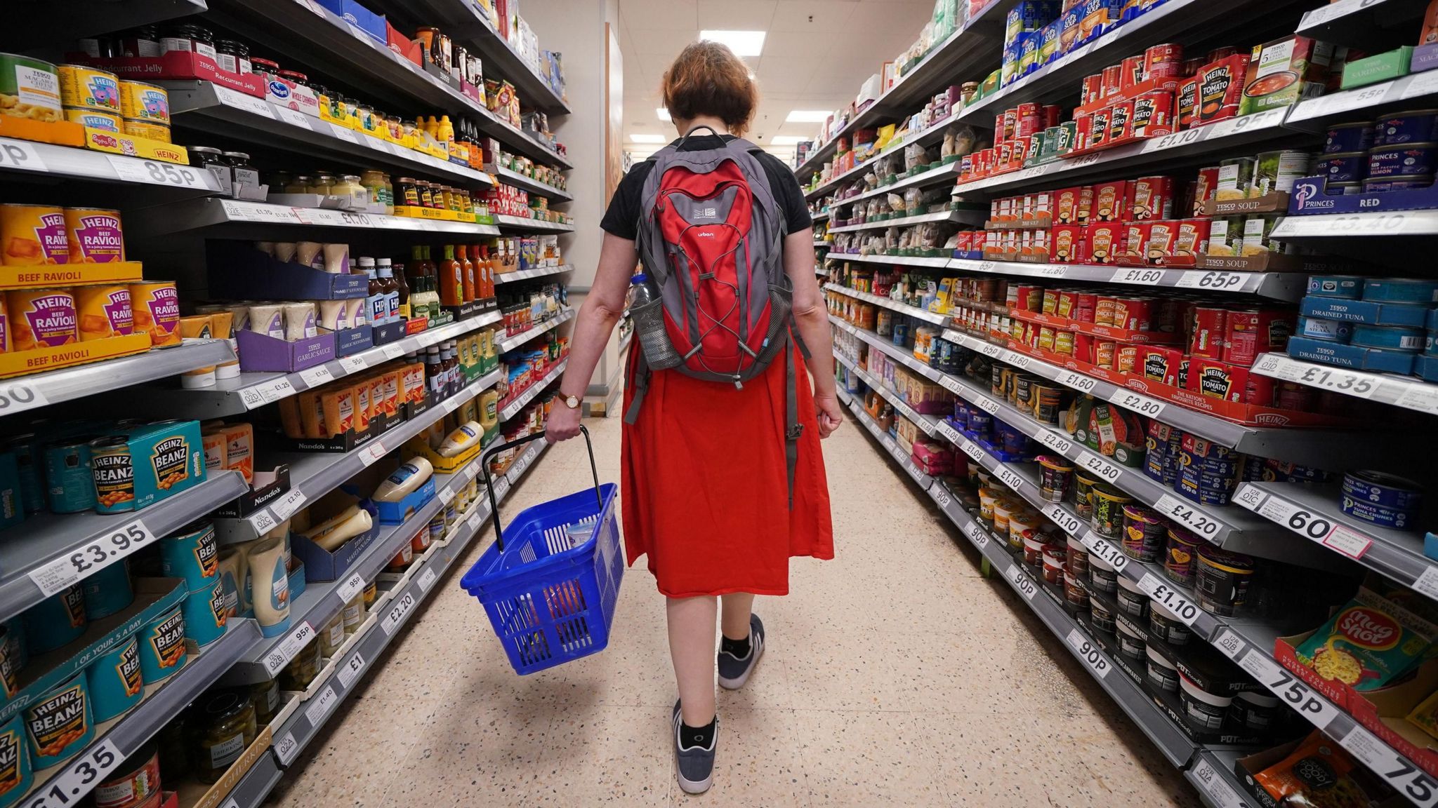 Woman walks through Tesco aisle holding basket