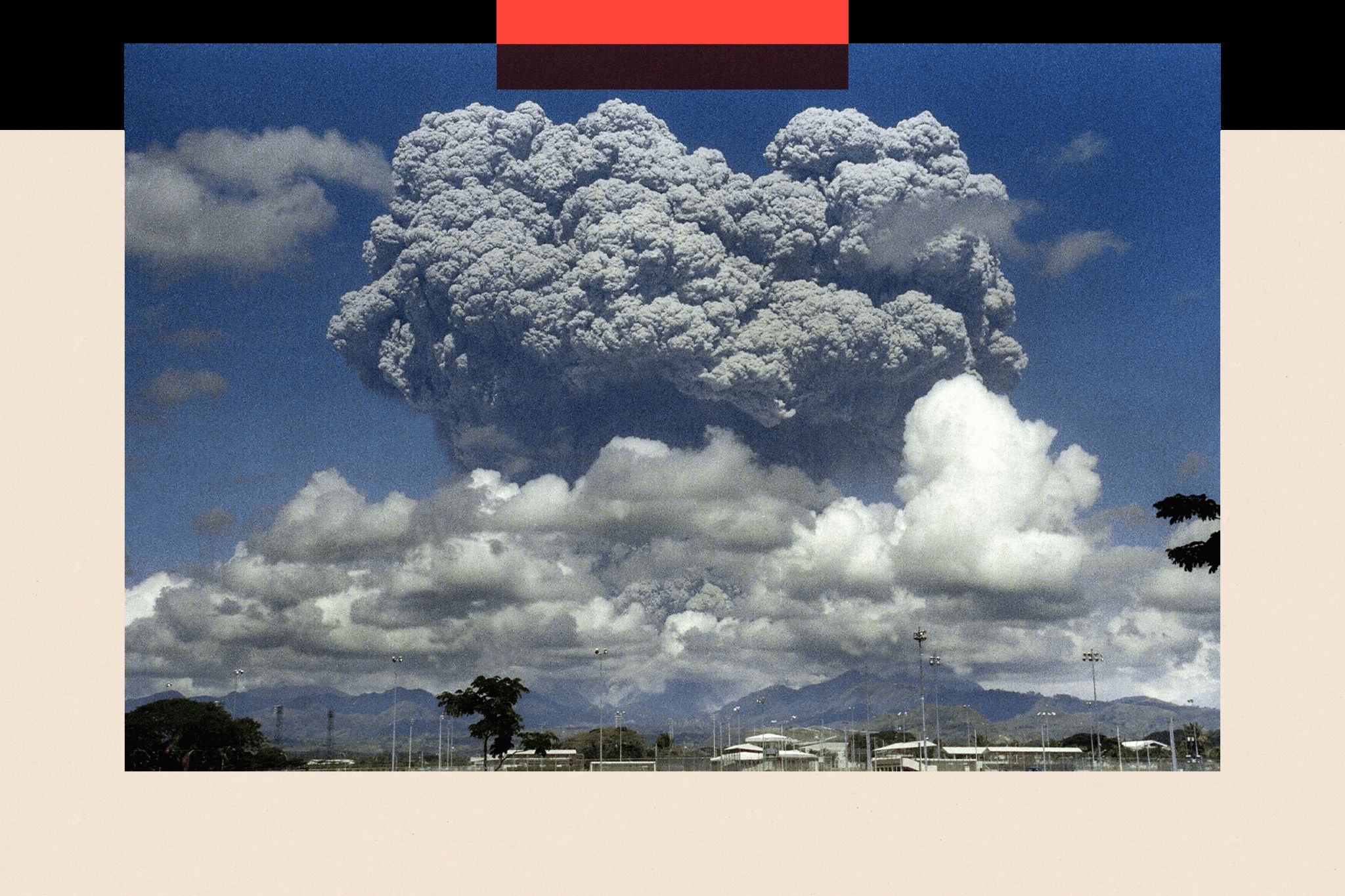 Mount Pinatubo with enormous grey clouds above it against a blue sky following its eruption in 1991