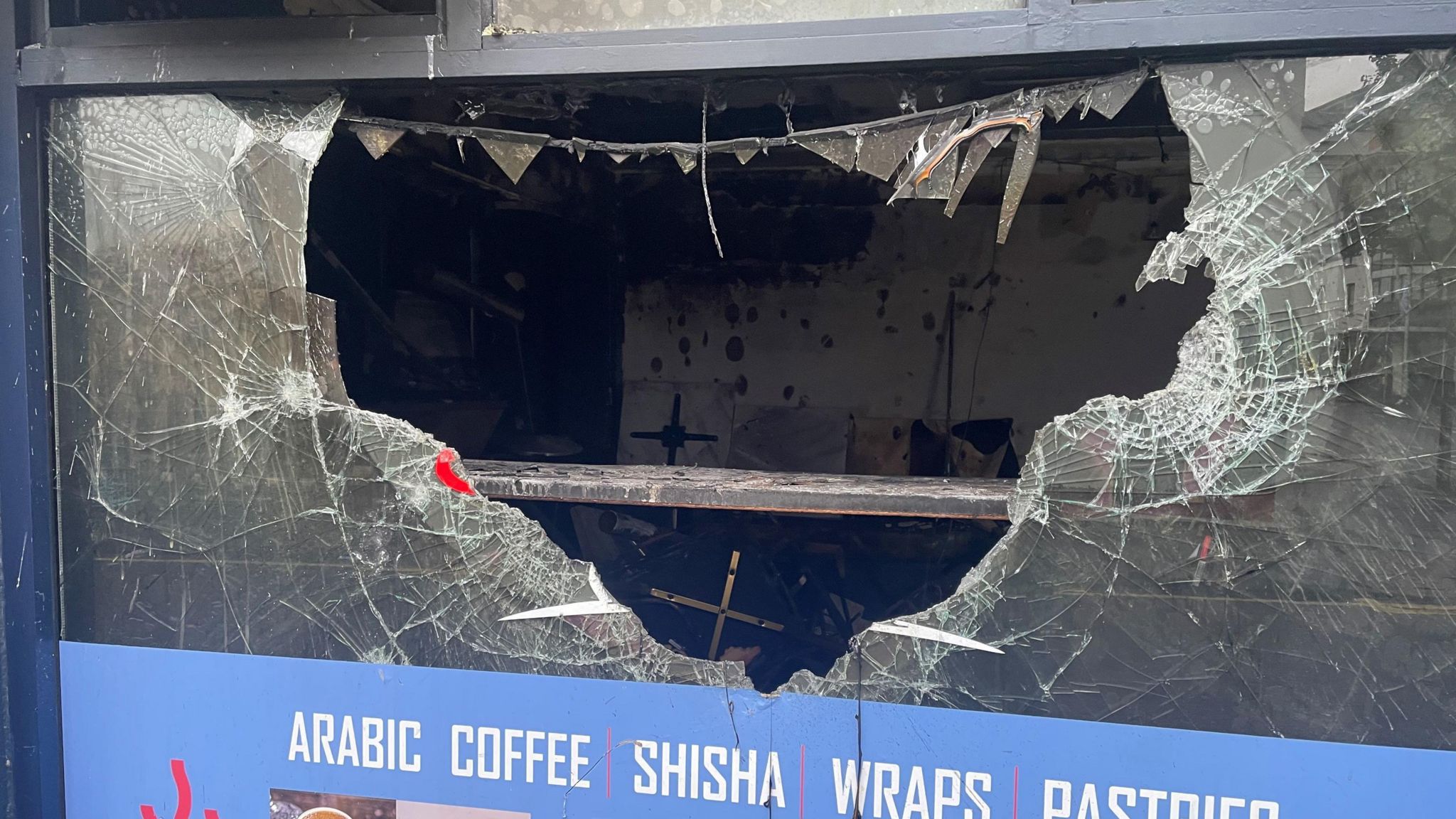 Image shows Bash Cafe with a hole in the window 