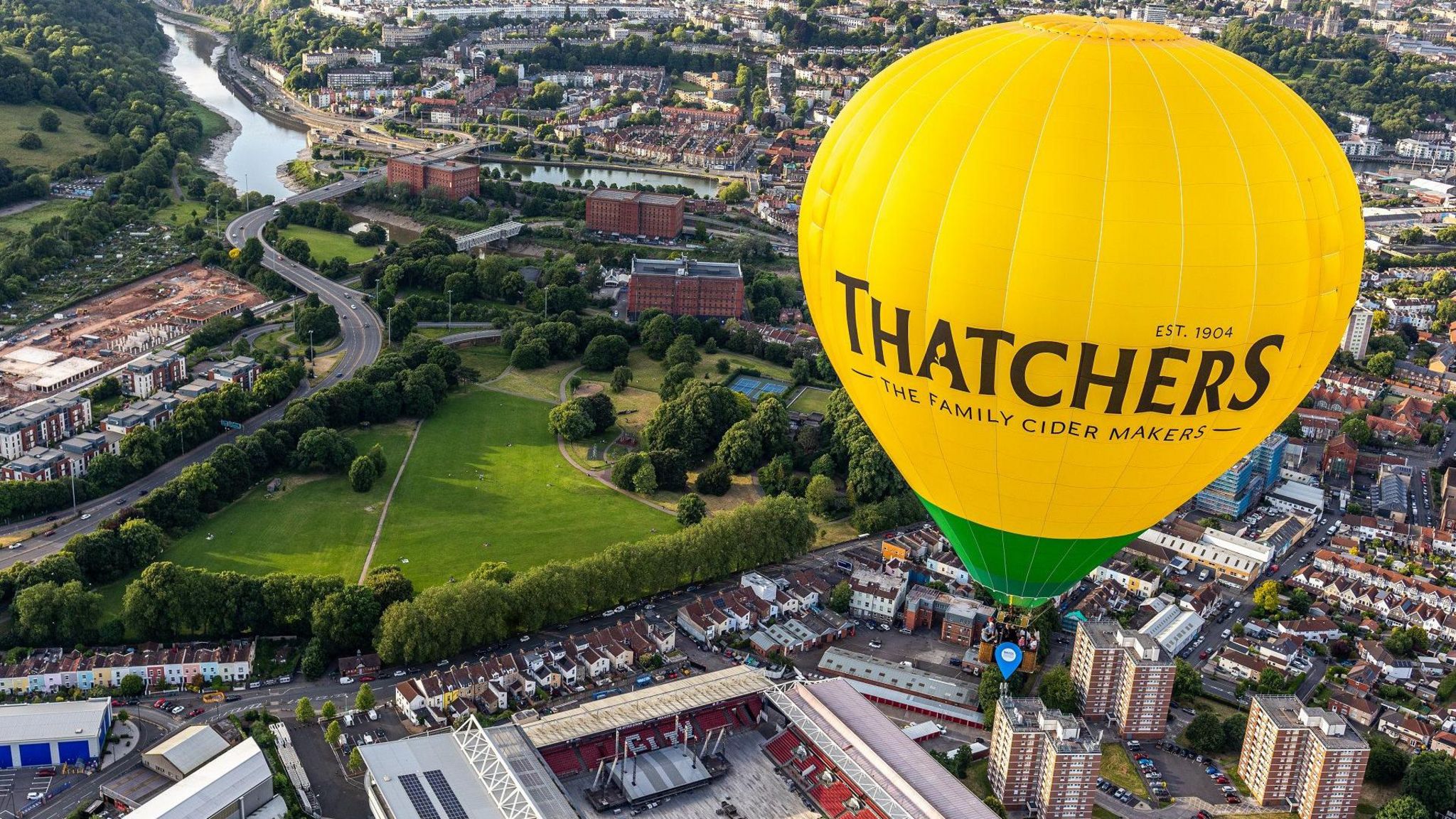 A Thatchers hot air balloon hovers over Ashton Gate Stadium in Bristol with the River Avon visible in the distance