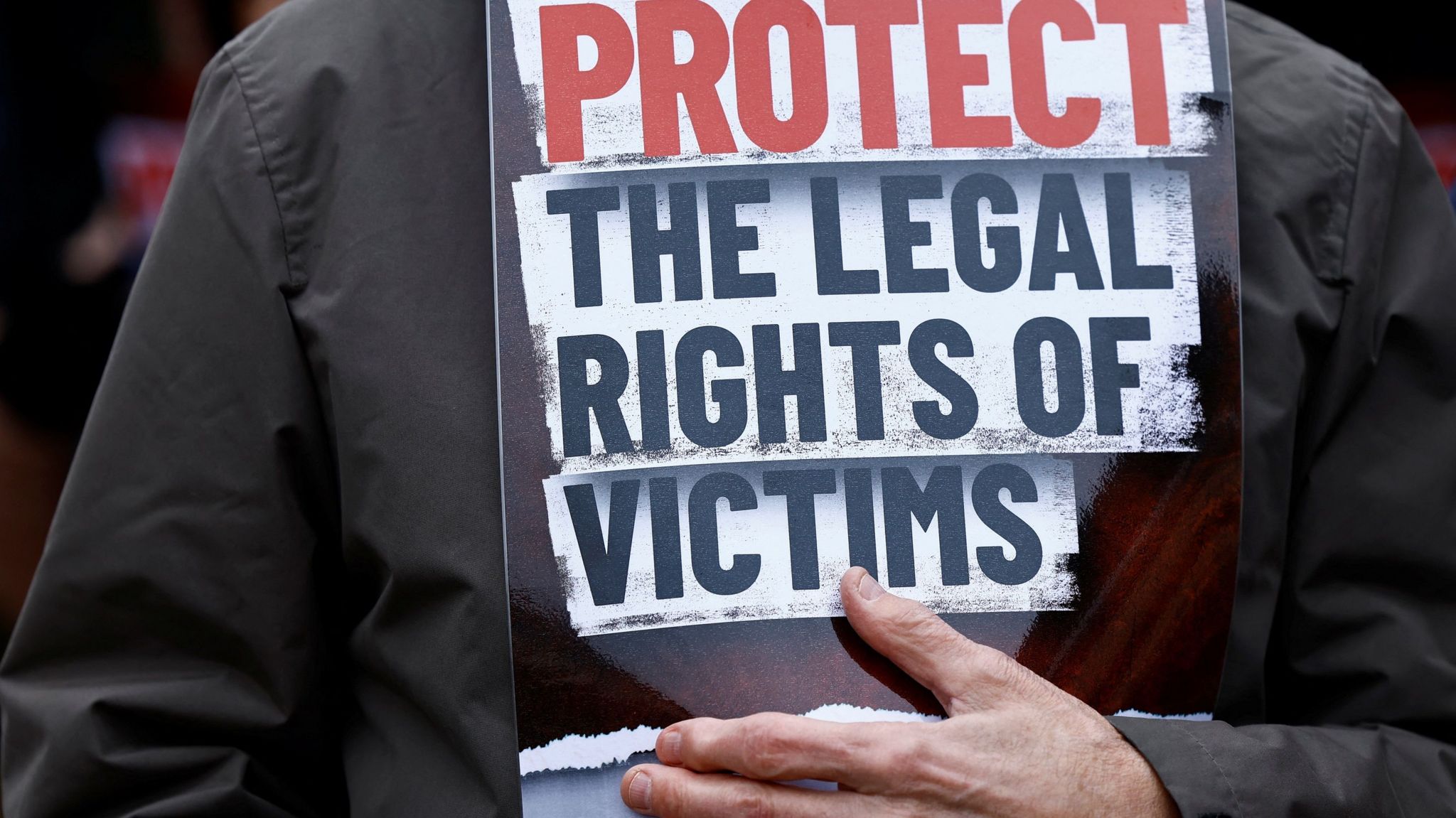 Man holding sign saying Protect the legal rights of victims
