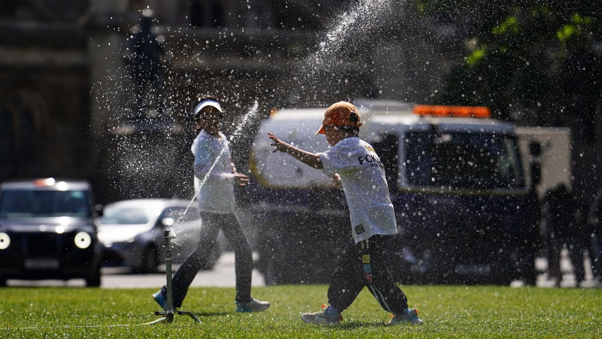 Children run through a sprinkler on Parliament Square in London,