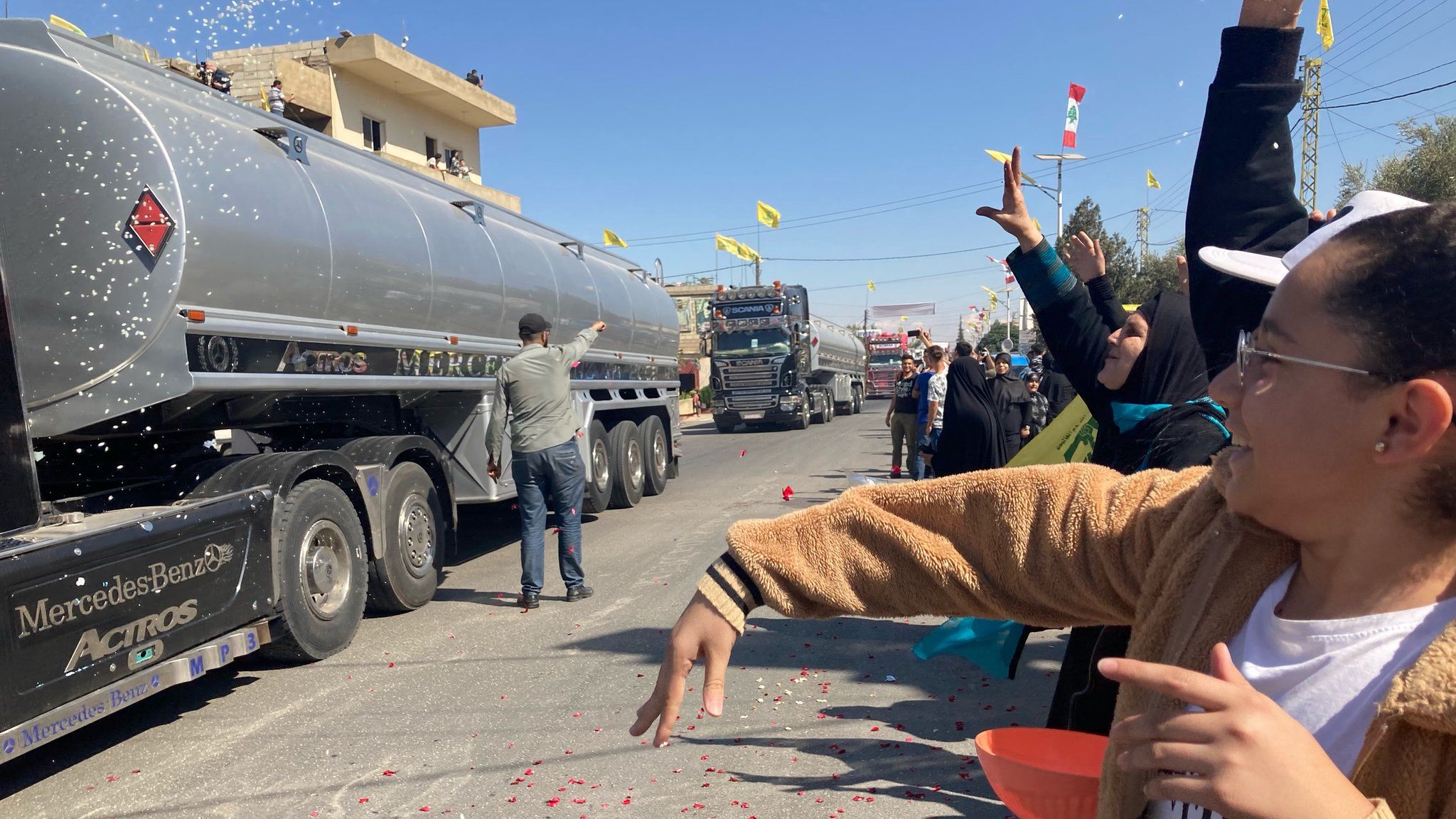Женщины бросают лепестки цветов в грузовики, привозящие иранское топливо из Сирии в Ливан, в деревне Аль-Айн (16 сентября 2021 г.)