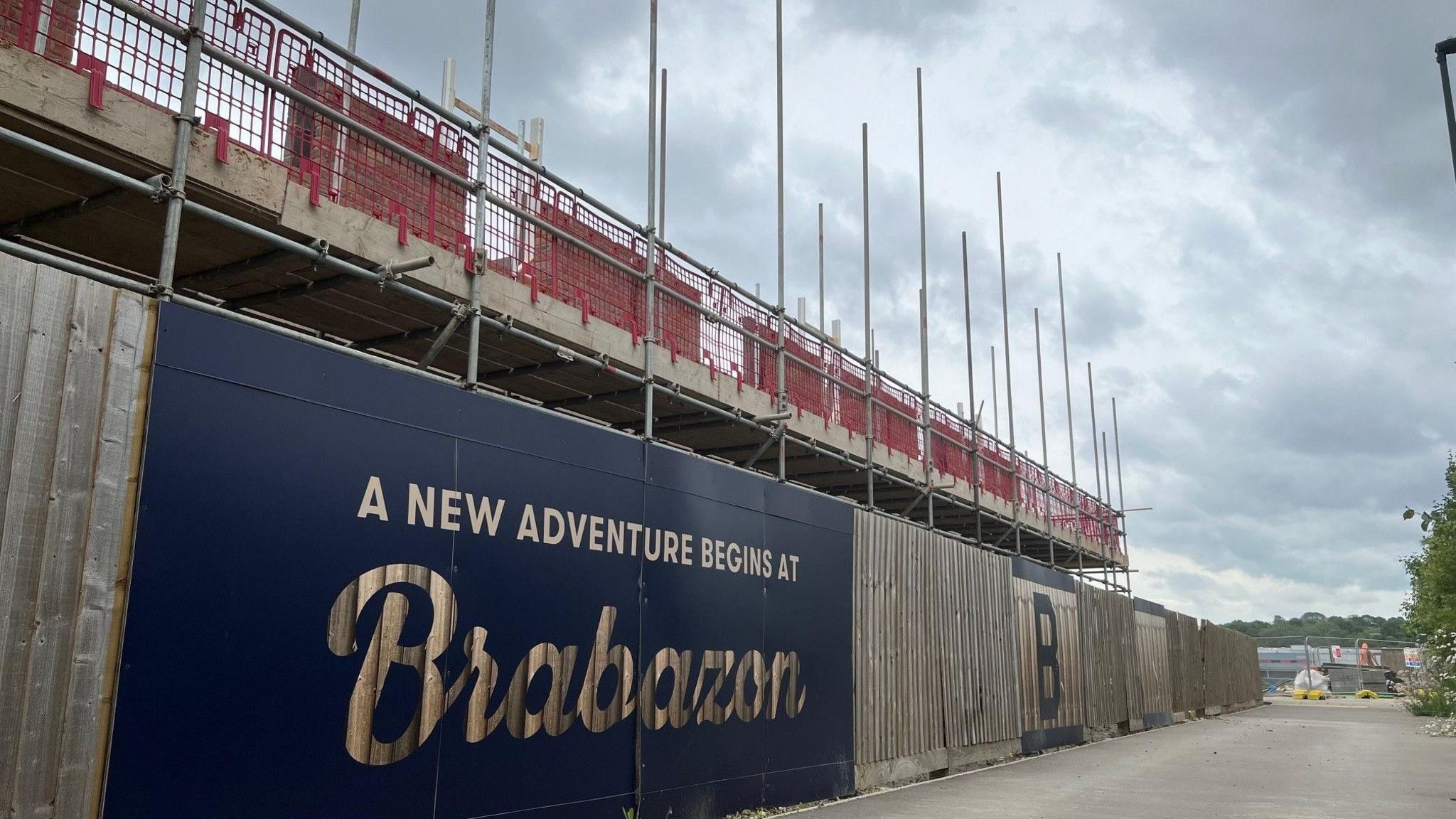 A sign saying "A new adventure begins at Brabazon" on a fence infront of new homes being built