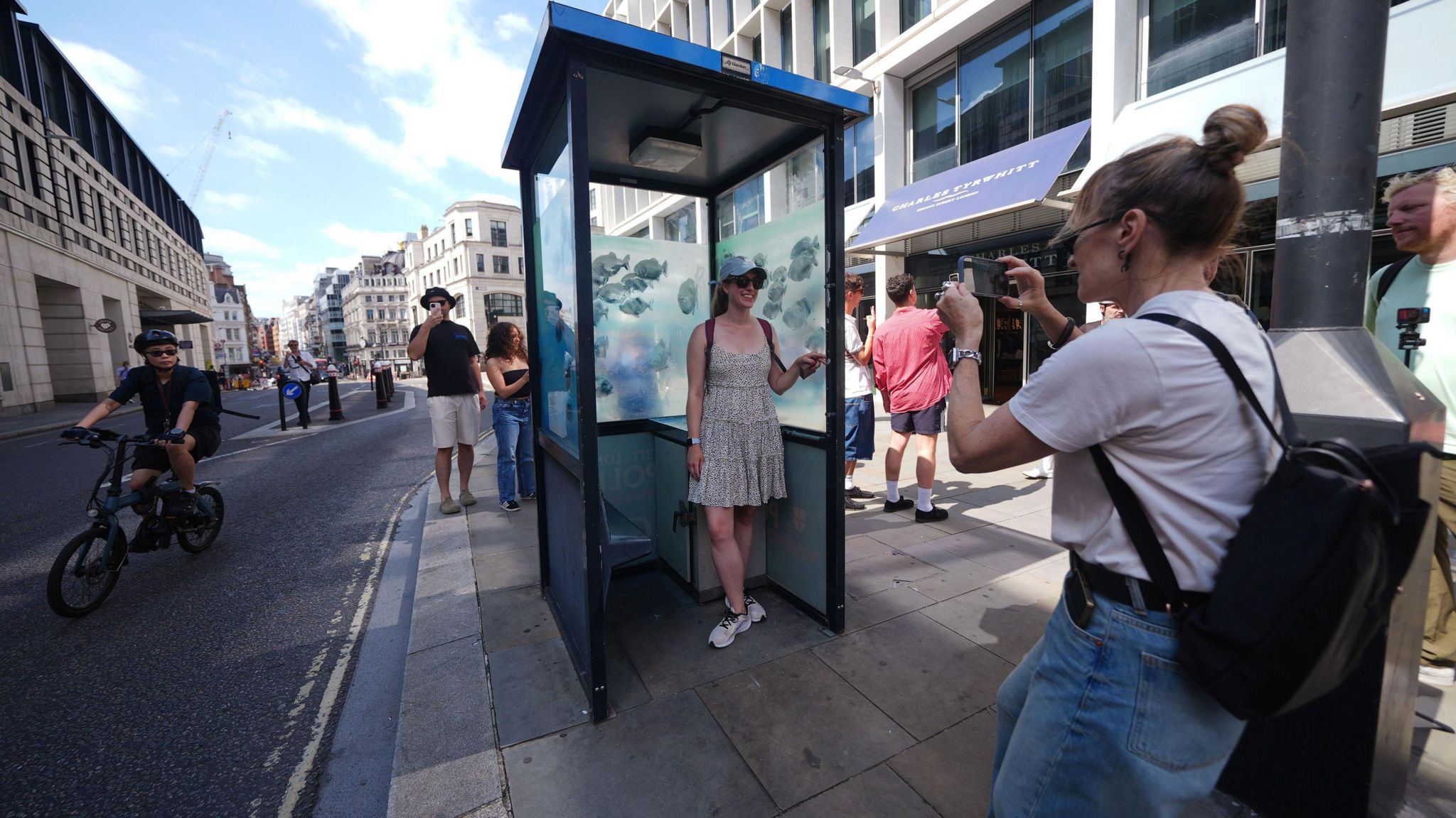 Woman having her photo taken inside the police box where the windows have been painted by Banksy