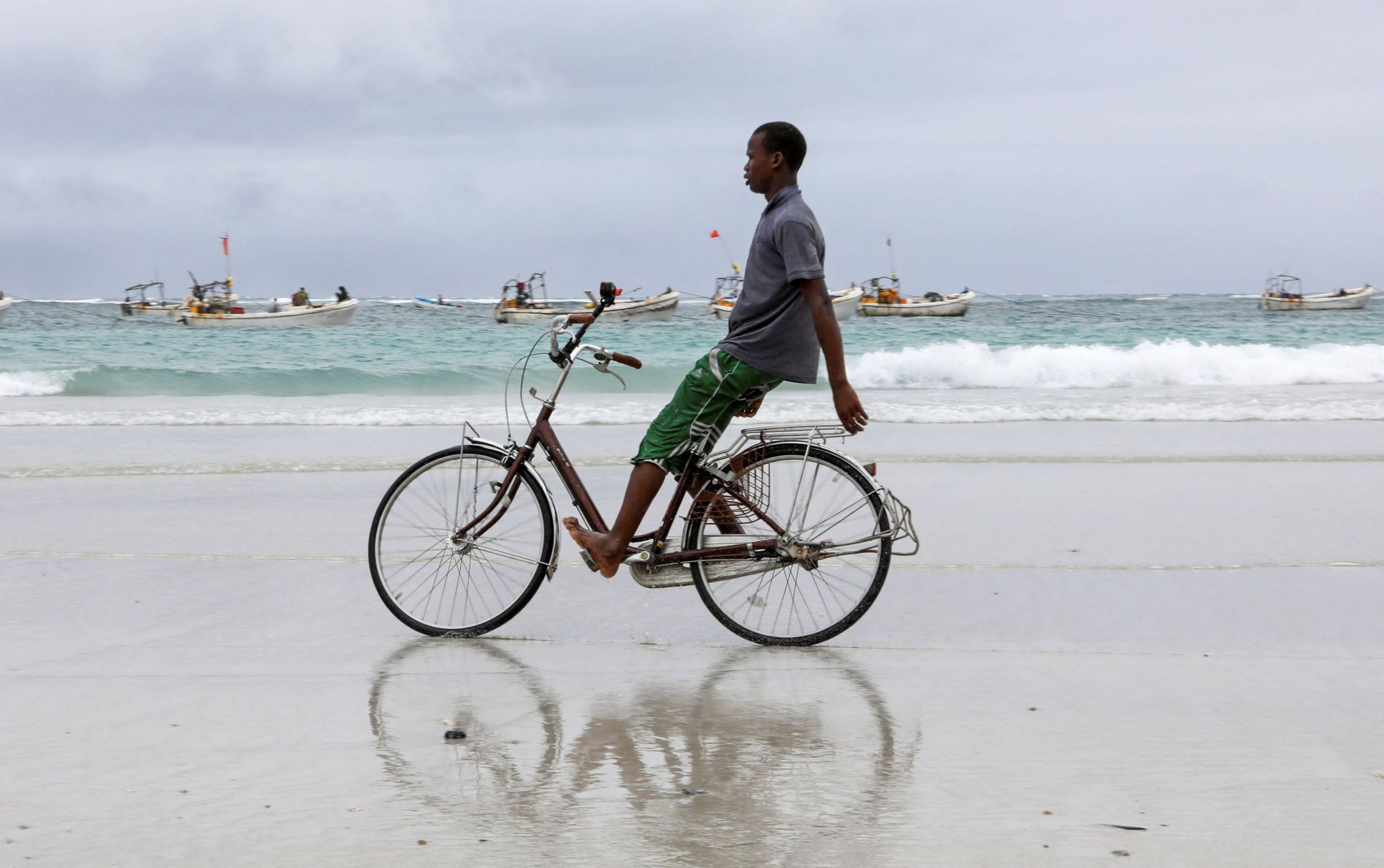 A boy rides a bicycle on a beach.